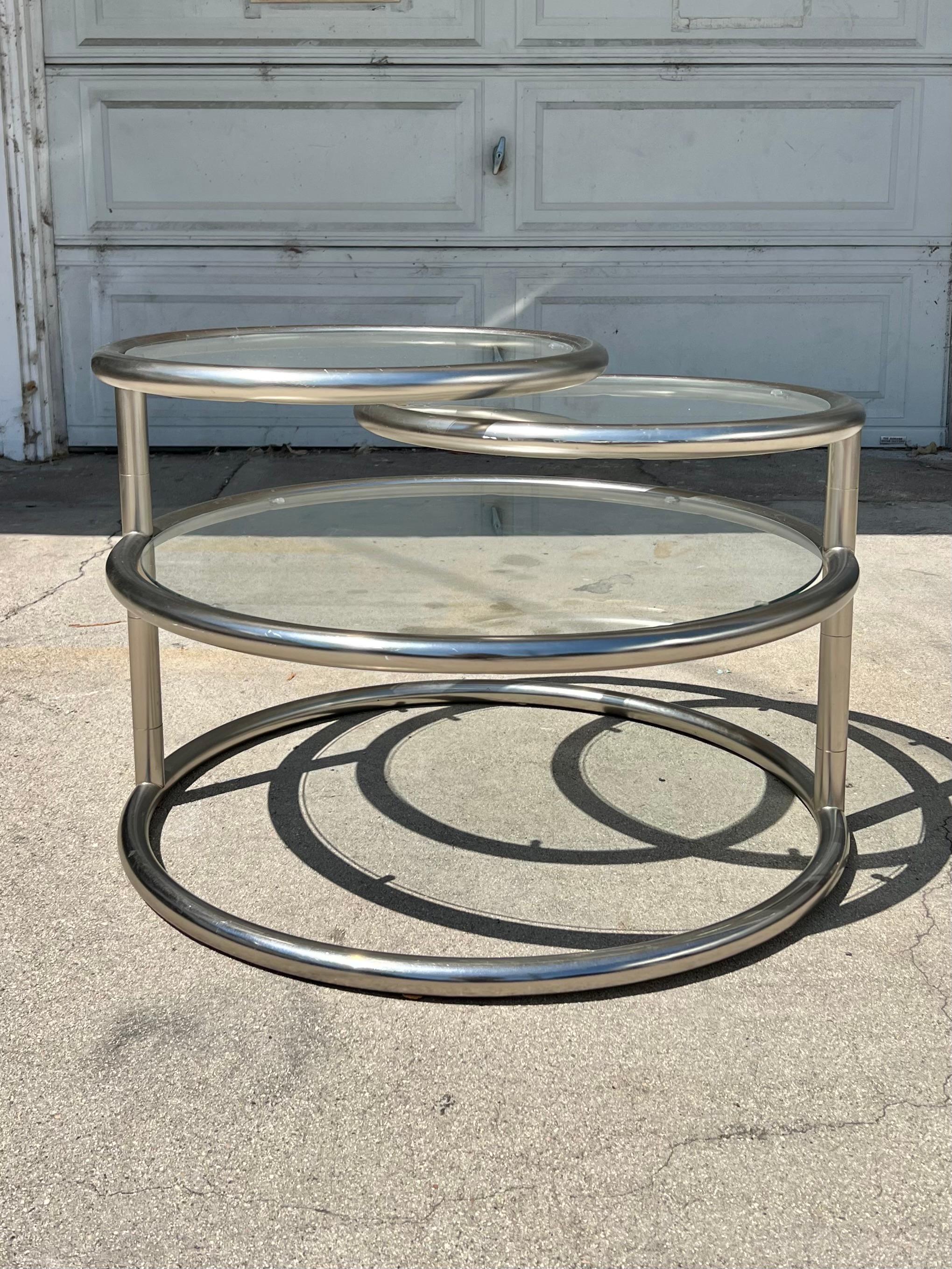 The original design of this tri level articulating coffee table is attributed to Milo Baughman, though this specific manufacturer takes the OG and adds a little more space age to it, widening the tubes and brushing the chrome.

 Overall excellent