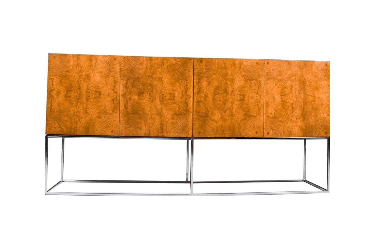 A stunning credenza / cabinet by Milo Baughman for Thayer Coggin, circa 1970’s. This exquisite piece features a beautiful burl wood finish with a simple chrome base and modern profile. The two double-door cabinets open by way of a spring latch for