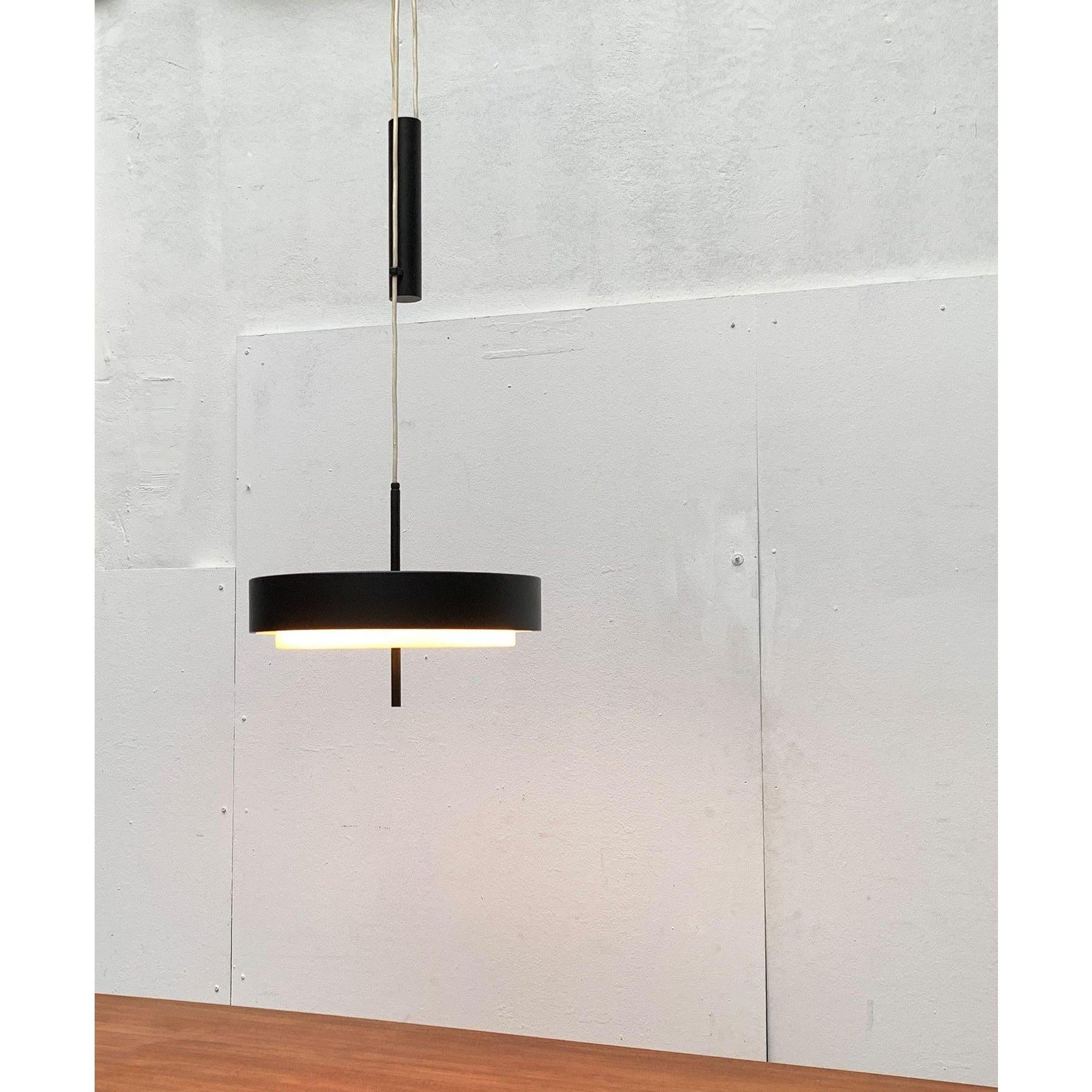 Pendolo minimalista di metà secolo con contrappeso.

Un design molto semplice e funzionale. La lampada è composta da un paralume rotondo in metallo nero e da un pannello diffusore in plastica traslucida. Il diffusore ha un diametro leggermente