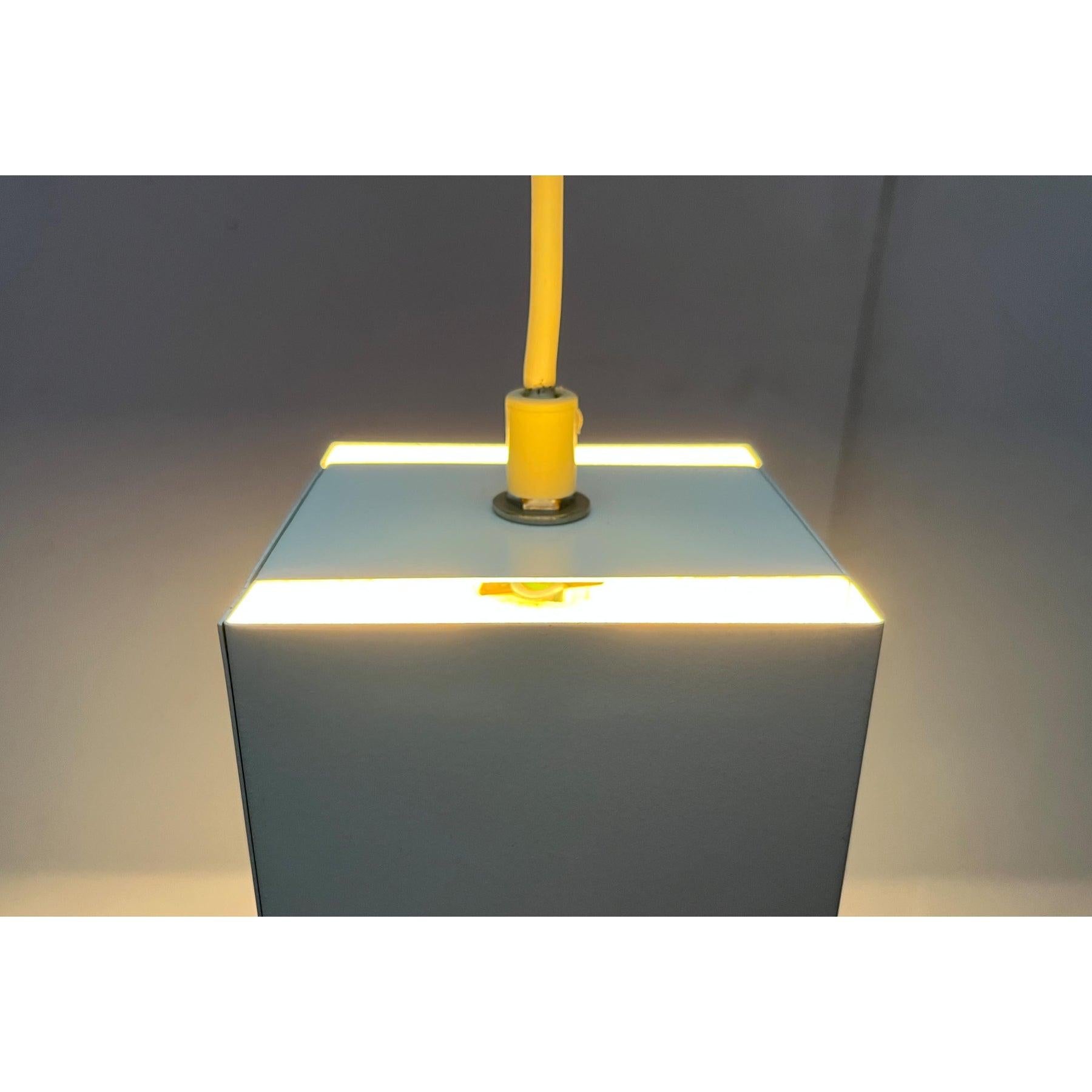 Simple mid-century pendant or recessed lights.

A minimalist design. The metal lamp body has a basic cubic shape. The minimalist look is supported by the completely white color scheme. Inside the lamp body there is a porcelain socket. Two wide slits