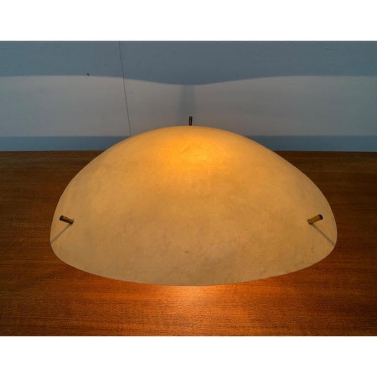 Grande plafoniera in fibra di vetro.

Un guscio piatto in fibra di vetro che si trova sotto il soffitto. Da un punto centrale partono dei puntoni a forma di ragno che sorreggono il guscio. Solo le teste di ottone delle viti penetrano nella