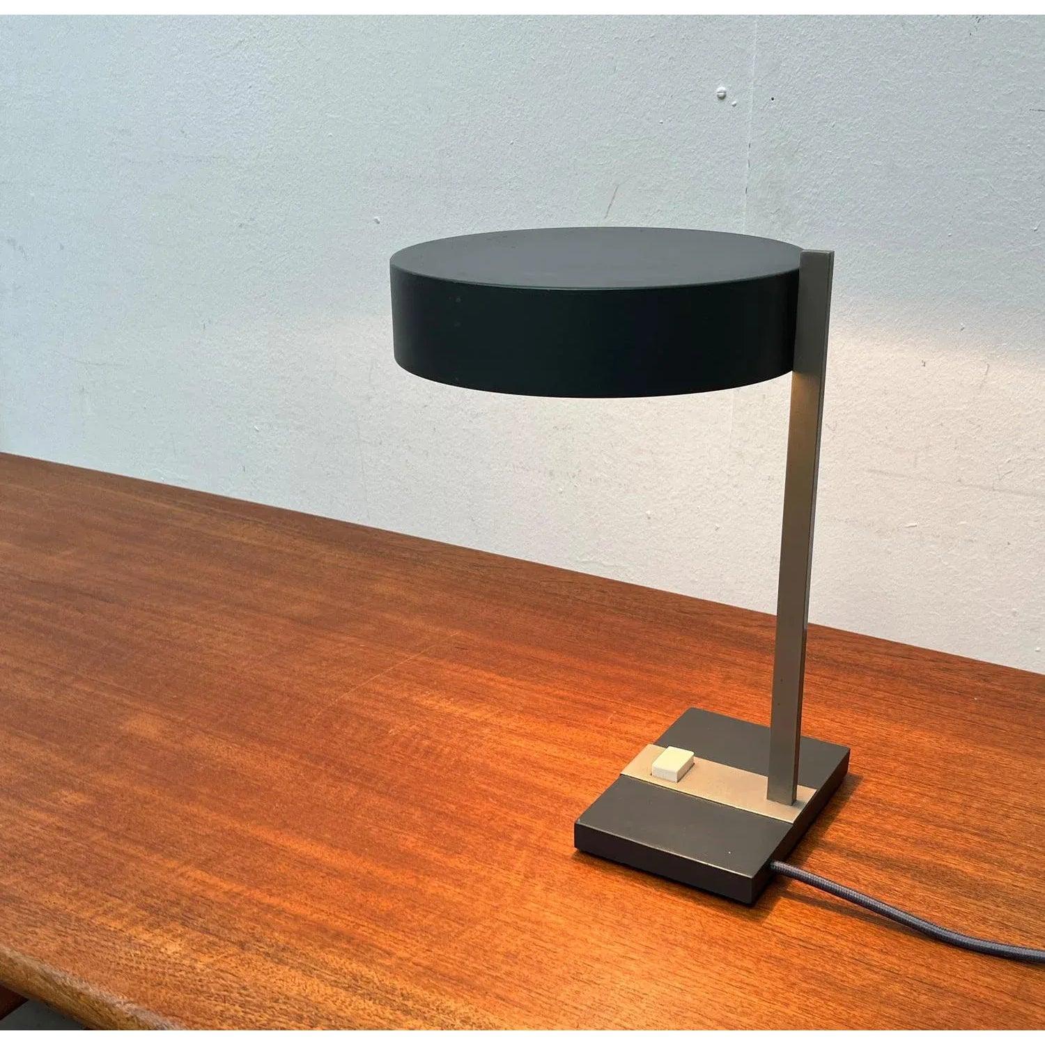 Minimalist mid-century table lamp by Hillebrand.

A minimalist design in shape and color. The shade is round. The base is a rectangular block. The shaft has a rectangular cross section. The white switch on the top is striking, as it fits into the