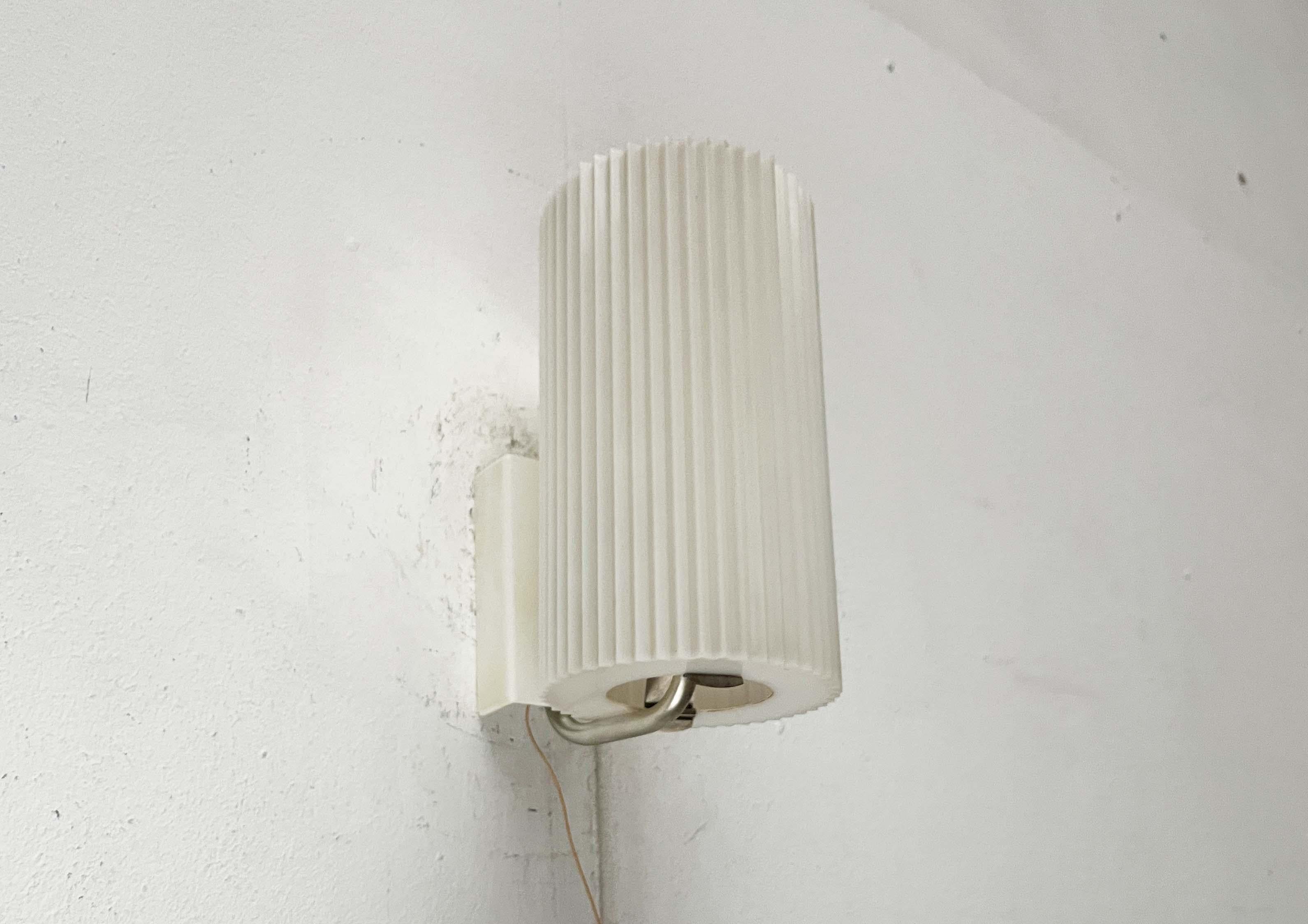 Rara lámpara de pared de Erco.

Un diseño minimalista. La pantalla cilíndrica es de plástico. Presenta una superficie estriada, que proporciona una luz difusa y sin deslumbramientos adicional. La pantalla se fija en la parte inferior con una
