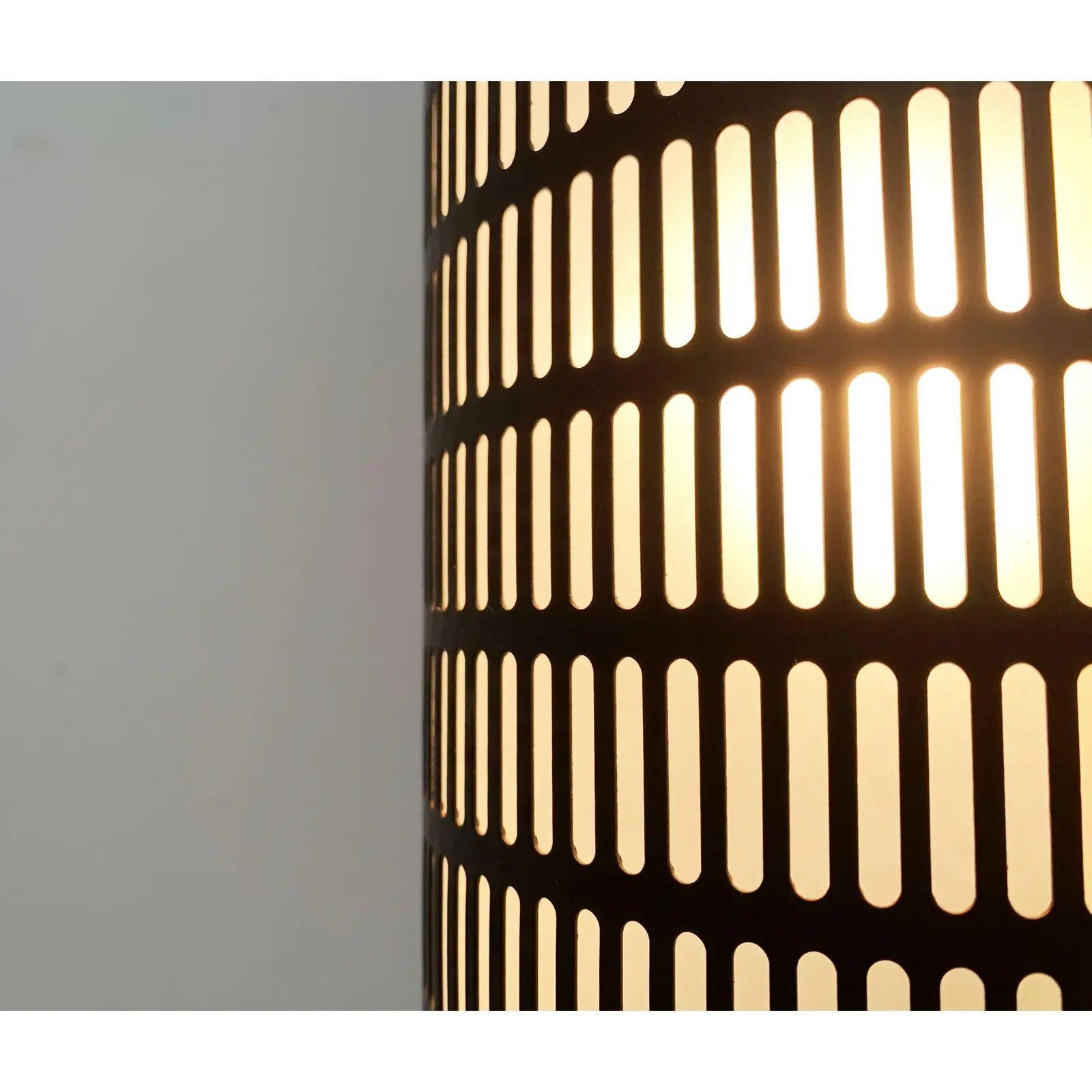 Lampada a sospensione minimalista con una suggestiva perforazione.

La semplice forma di base del cilindro viene spezzata da una perforazione simmetrica a foro lungo. La lampada è aperta e rilascia luce diretta. Il corpo luminoso è nero opaco.