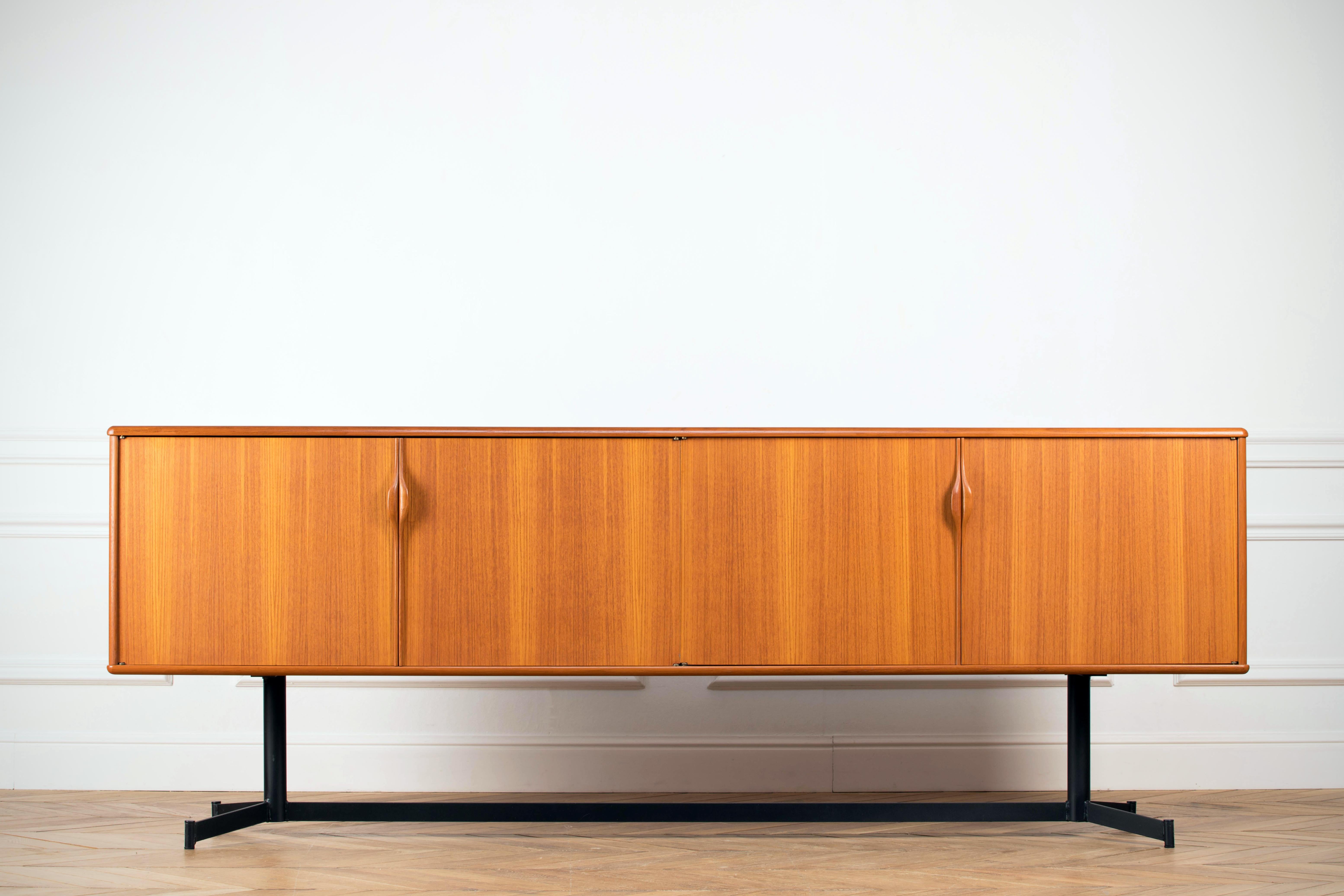 Midcentury teak sideboard from the 1960s. It is a shining example of the form and function synonymous with furniture of this era. It has is all; well-built, great design and heaviness. Four doors hiding storage space. The most remarkable aspect of