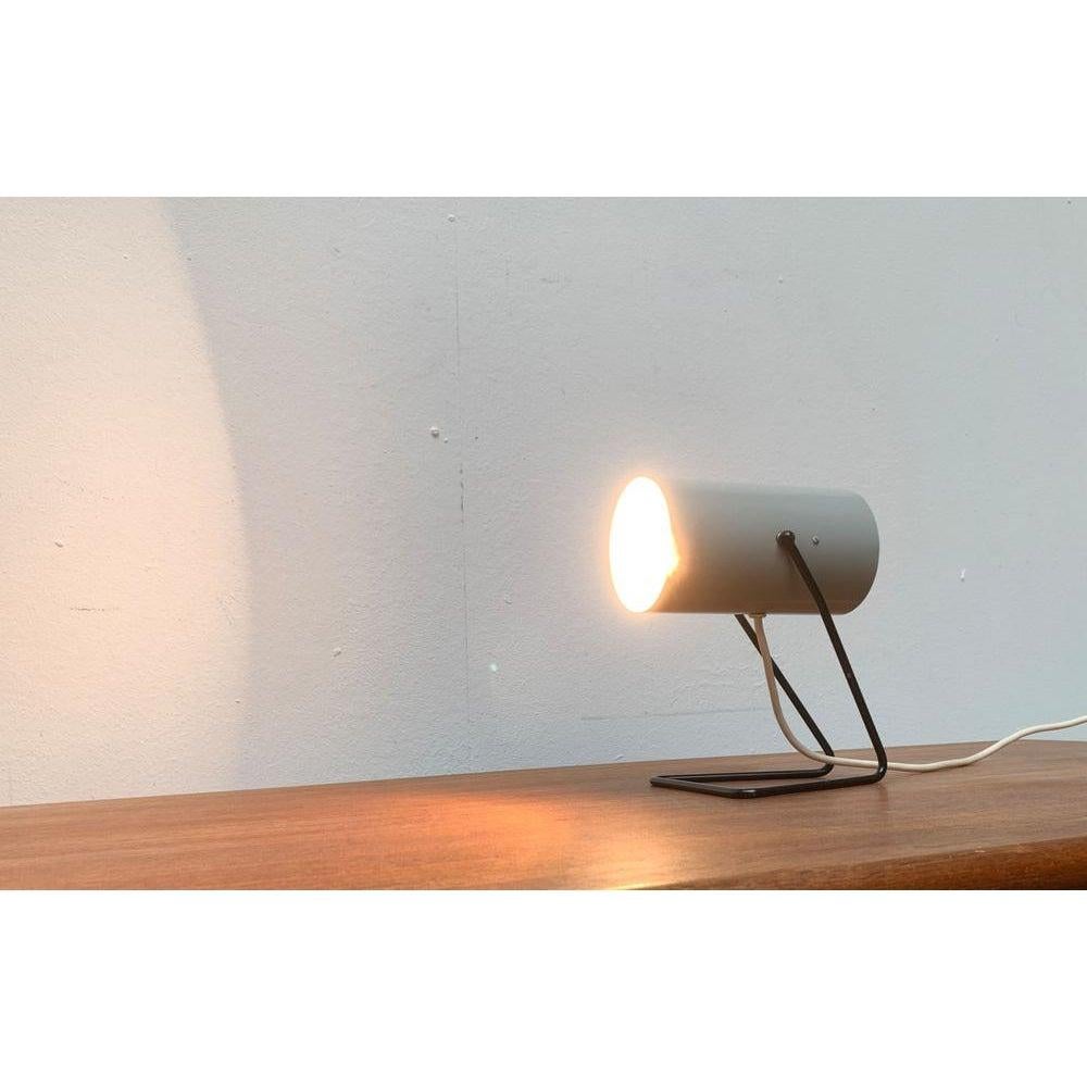 Rara lámpara de mesa de mediados de siglo.

Un diseño de luminaria minimalista. La luminaria consiste en un simple reflector cilíndrico. La parte delantera del reflector está abierta, la trasera está casi cerrada hasta la ranura de ventilación
