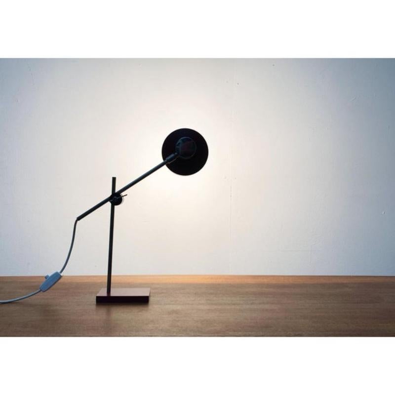 Petite lampe de table du milieu du siècle.

Un design minimaliste dans une couleur particulière. La tête d'éclairage est reliée au bras par une articulation à rotule. L'écran réflecteur est conçu dans un ton rouge foncé. La couleur est répétée dans