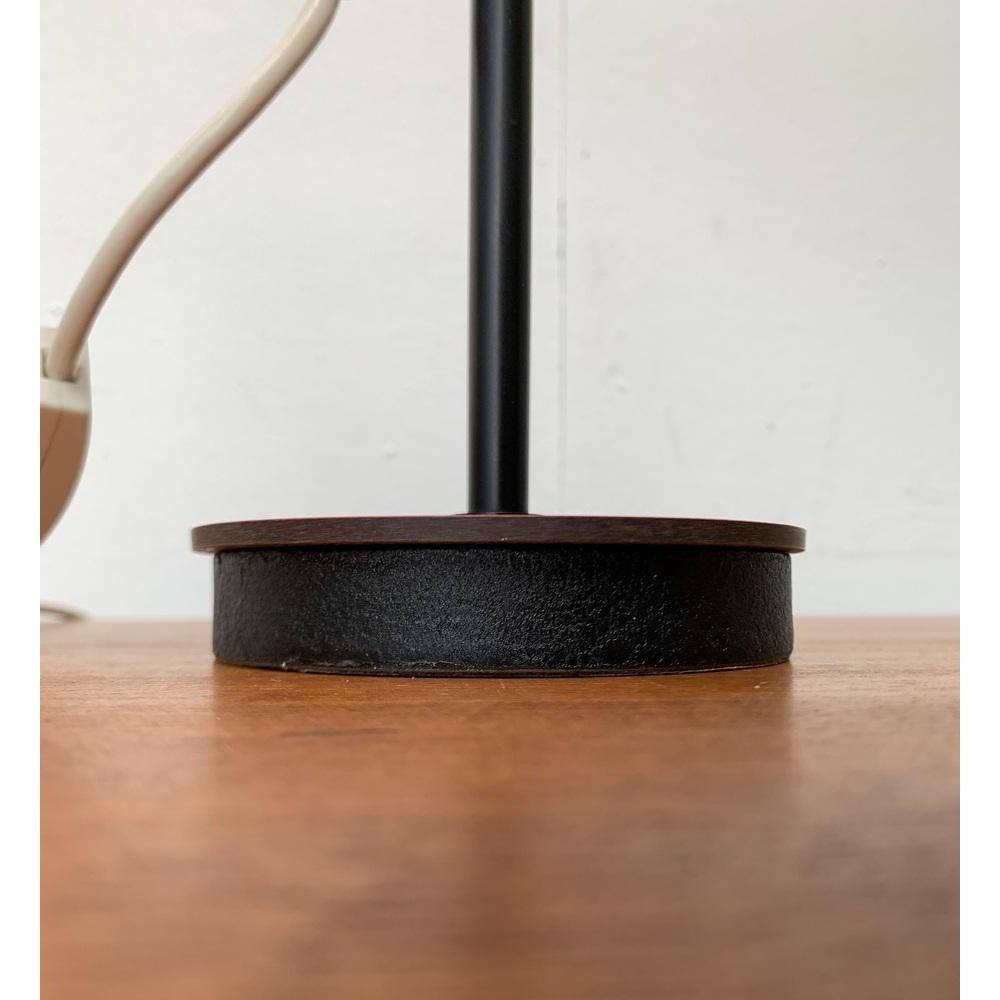Lámpara de sobremesa de mediados de siglo con un llamativo pie.

Un diseño minimalista con detalles decorativos. El eje de la lámpara está dividido en dos. La zona inferior termina en el pie y lleva un manguito en la zona superior. Está conectado al