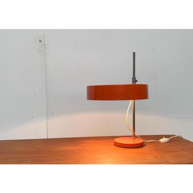 Rare Mid Century table lamp.

A minimalist design in a matter-of-fact design language. The shade shows the shape of a flat cylinder. The simple design of the shade is repeated in shape and color in the base. The two elements of the lamp are