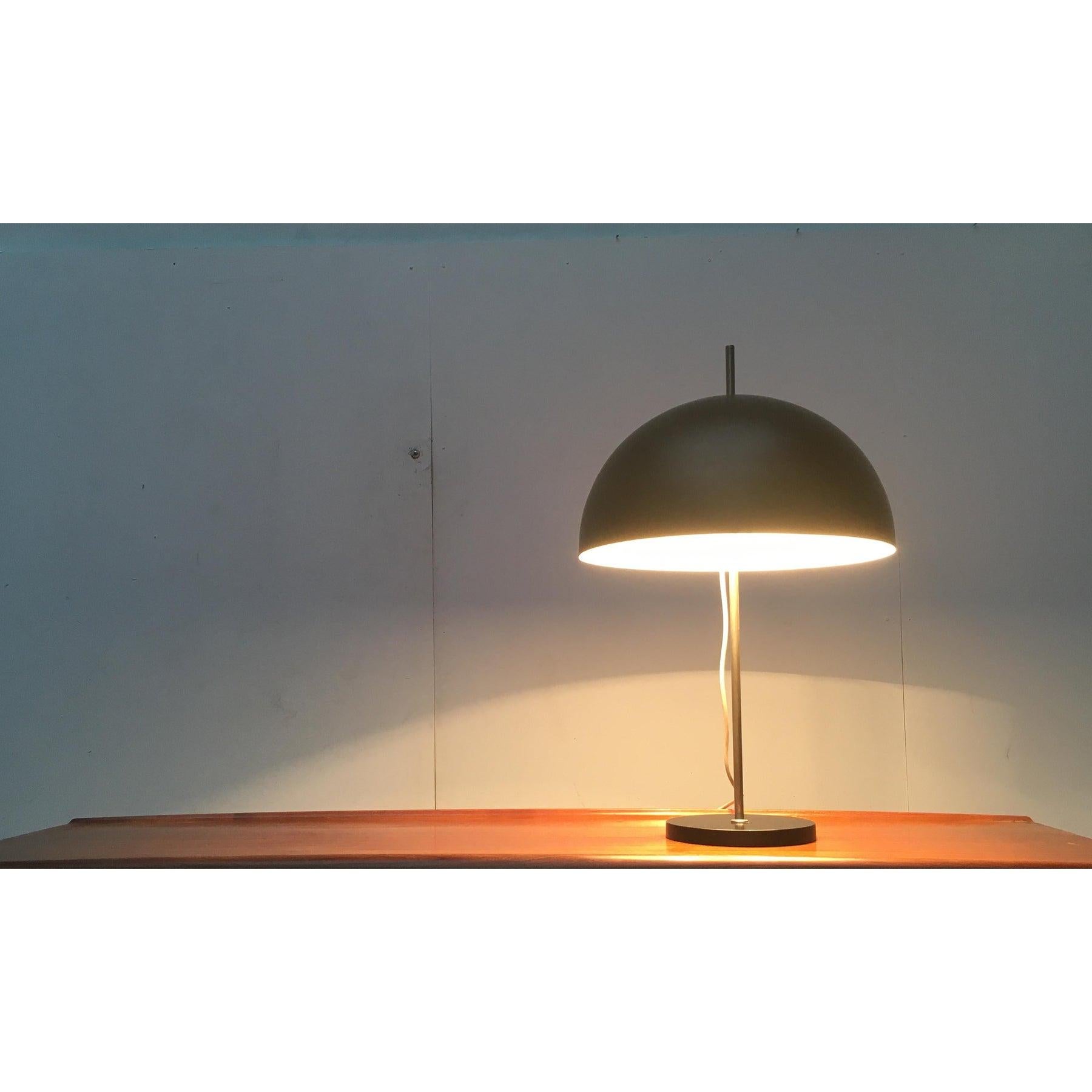 Mid-Century table lamp.

A minimalist design. The large shade shows a simple hemispherical shape and is finished in black. The same design language and color is found in the simple plate base. The shade can be adjusted in height at the stem, which