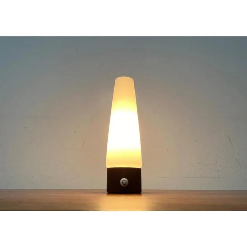Lampe de table du milieu du siècle en verre et en teck.

La lampe se compose de deux parties. La base et le verre du diffuseur. La base est plaquée de teck et comporte un interrupteur à pression sur le devant. Le verre se rétrécit vers le haut. Il
