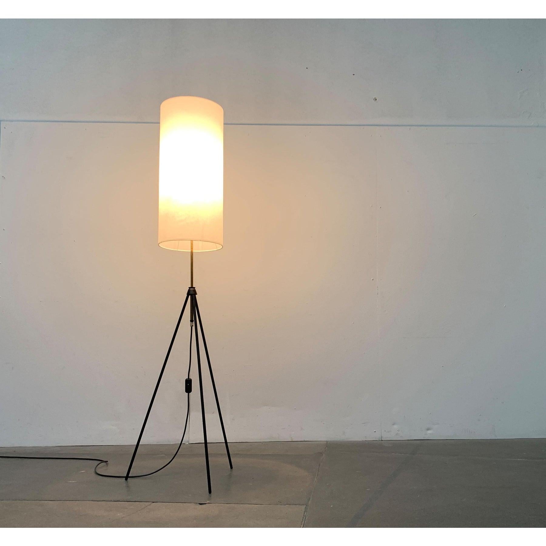 Lampada da terra minimalista a treppiede.

Un design in filigrana. L'ombrello ha una forma cilindrica sottile ed è ricoperto da una pergamena leggera. Si trova su un ottone finemente lavorato che scorre in modo mobile attraverso un elemento