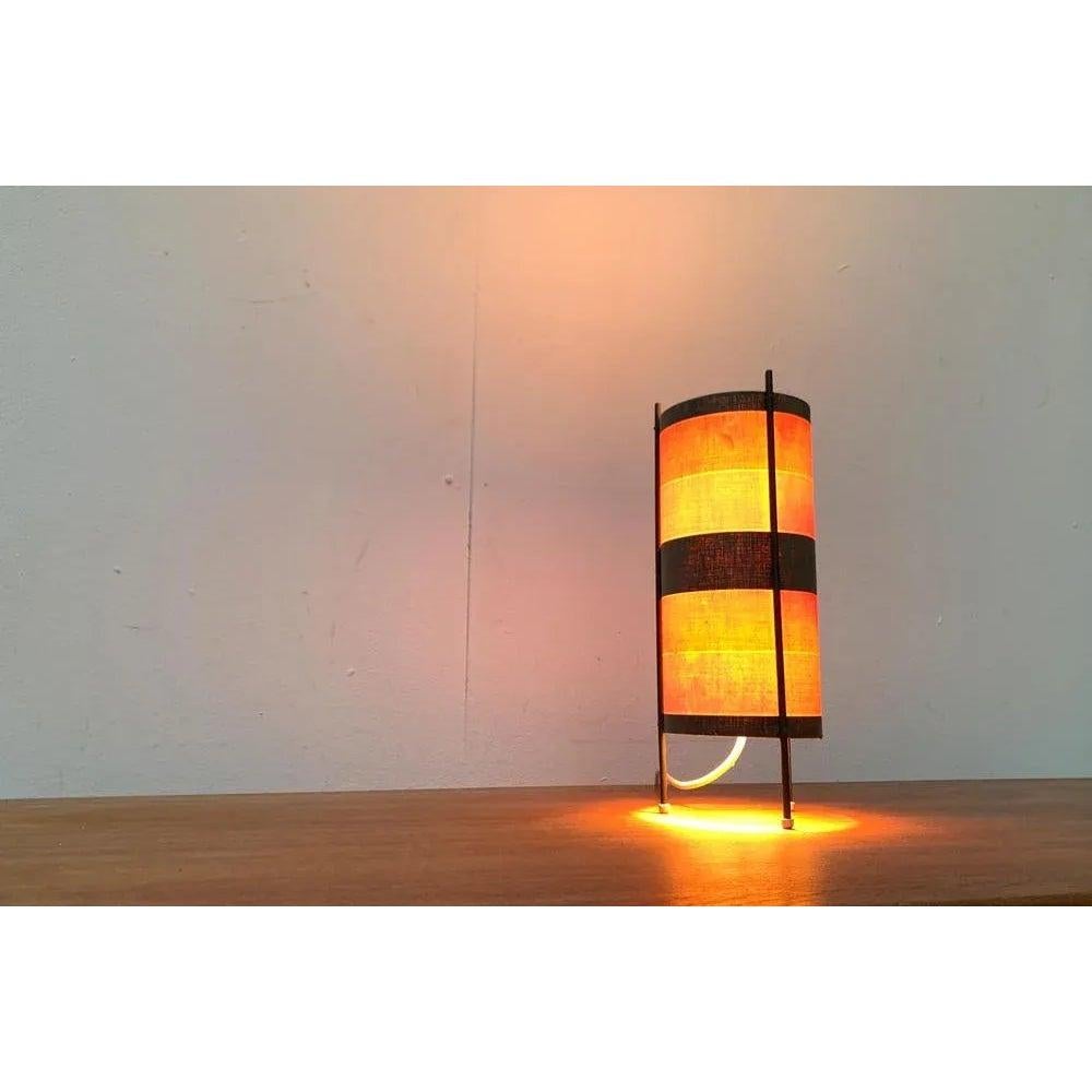 Mid Century Tripod table lamp with a special pattern. A simple design. The umbrella forms a simple cylinder that is held and upset from the outside. The rods are over on the top. The strip pattern of the original shade is striking. Unfortunately,