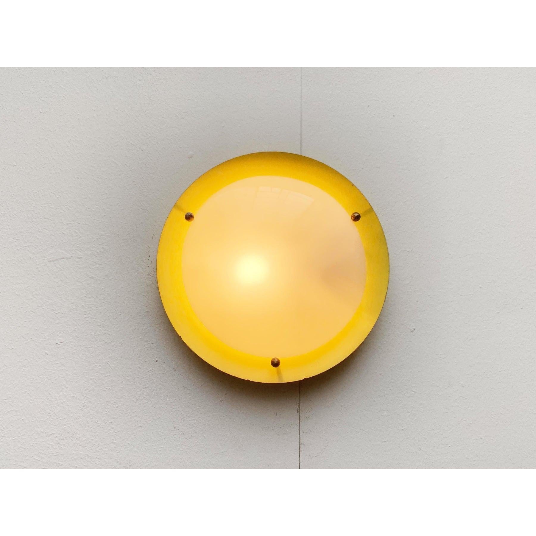 Lámpara de pared o de techo Mid Century.

Un diseño sencillo. Una placa plana como reflector sobre la que se asienta un disco acrílico ligeramente convexo como difusor. El difusor se sujeta con tres bolas de latón.
Hasta 250 V (norma Europa/Reino