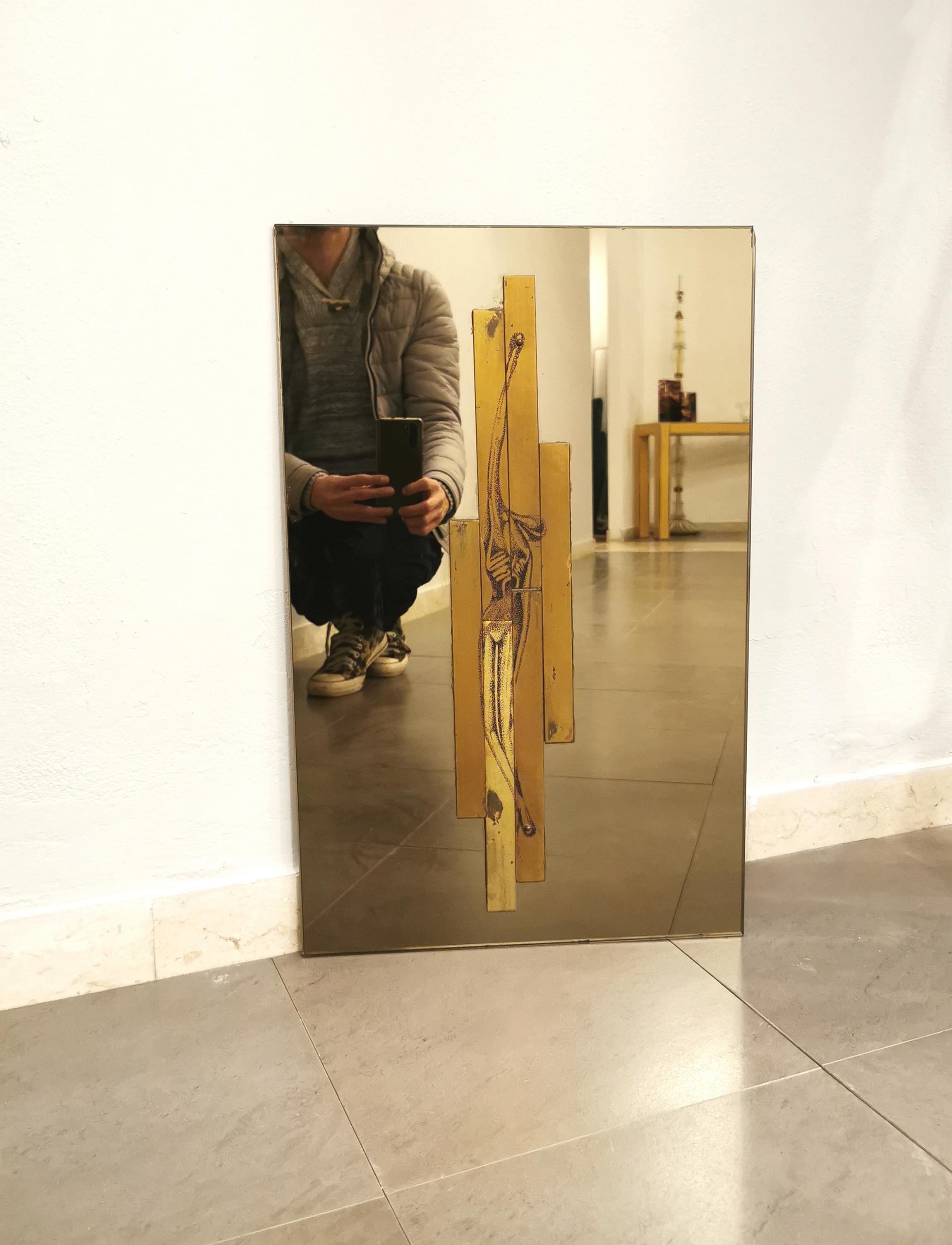 Particular and unique rectangular shaped wall sculpture by the unknown designer in caramel-colored mirrored glass with brass plates screwed to the center of the mirror, where the drawing of a human body is depicted. Made in Italy in the 70s.