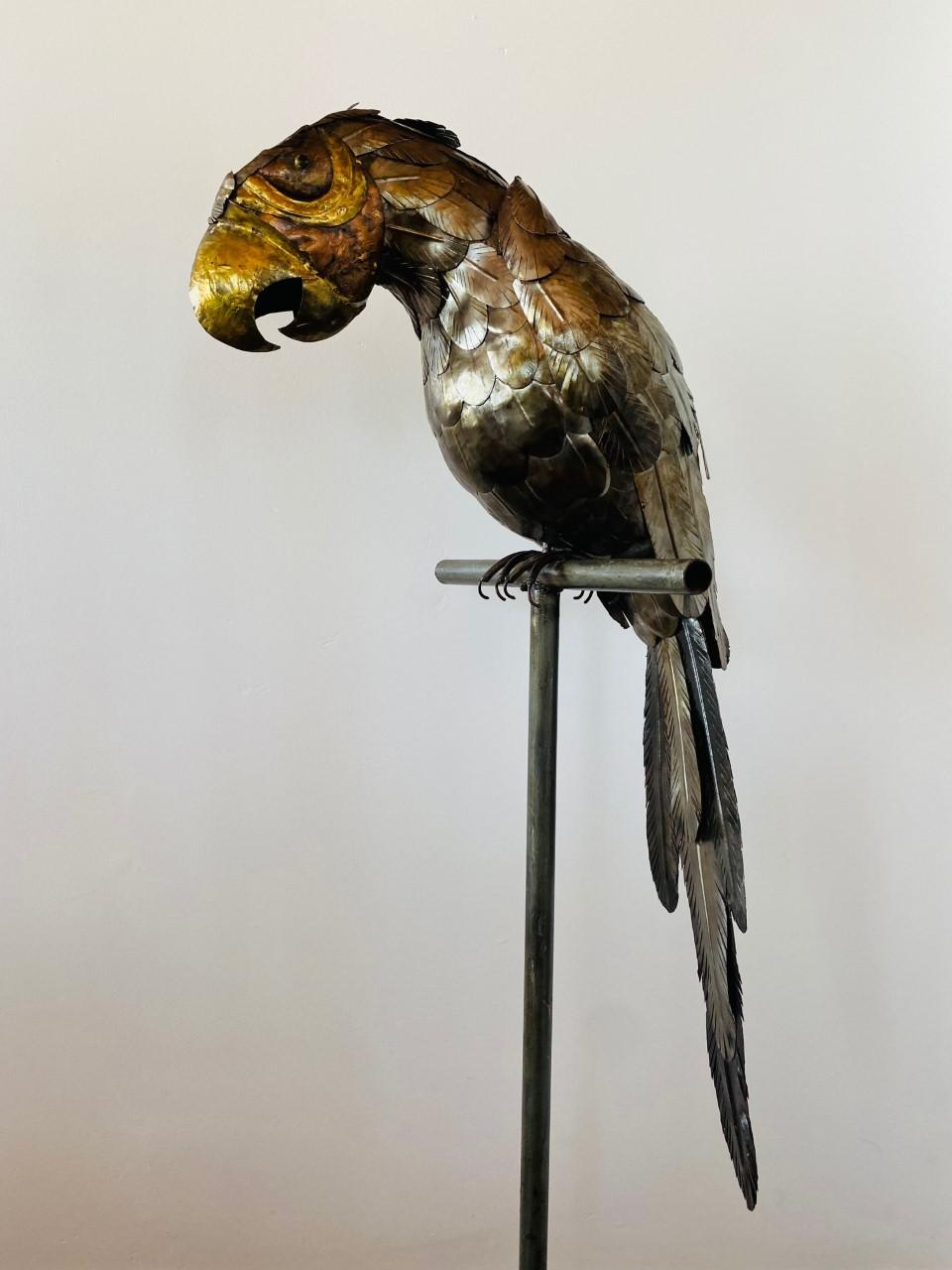 Oiseau perroquet sculptural sur perchoir en métal, réalisé en métaux mixtes (cuivre, laiton). Cette pièce des années 1970 suit le style de Sergio Bustamante. Le mélange de métaux ajoute de l'éclat et de la profondeur à la forme, et les détails sur
