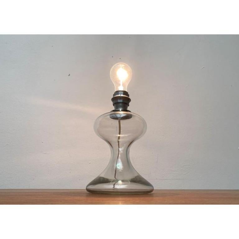 An early design by the well-known luminous designer Ingo Maurer from the late 1960s.

An elegant and classic design. The ornamental foot is designed in clear glass. The original screen is no longer available, but can be replaced by a commercially