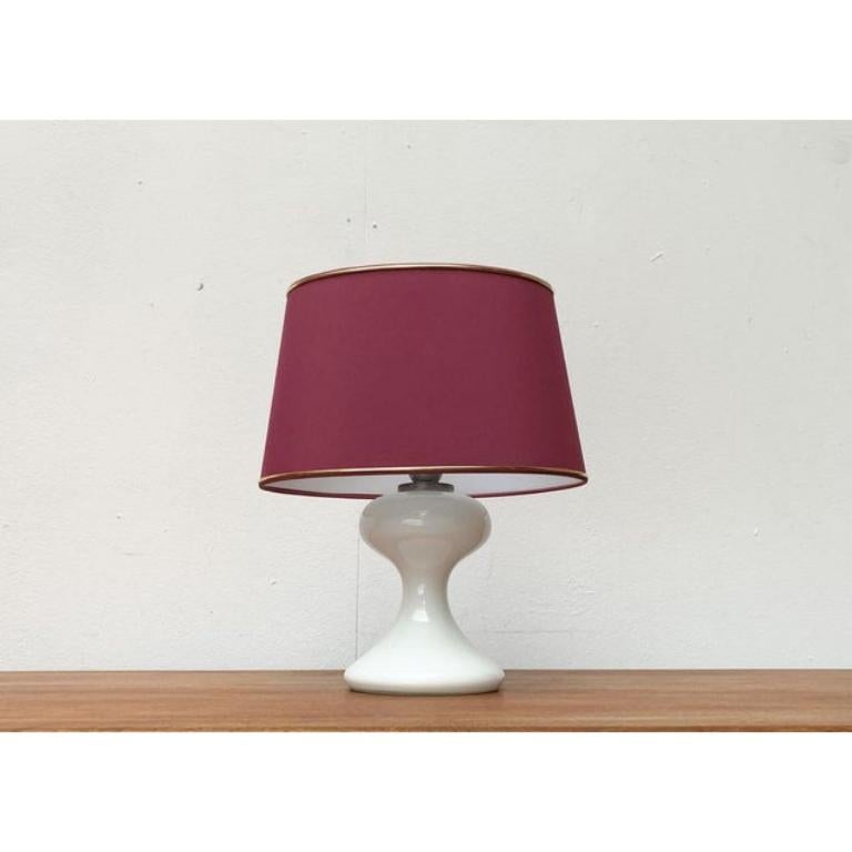 Une des premières créations du célèbre designer de luminaires Ingo Maurer datant de la fin des années 1960.

Un design élégant et classique. Le pied ornemental est conçu en verre blanc. Le parapluie a une forme ovale. Il est recouvert d'un tissu