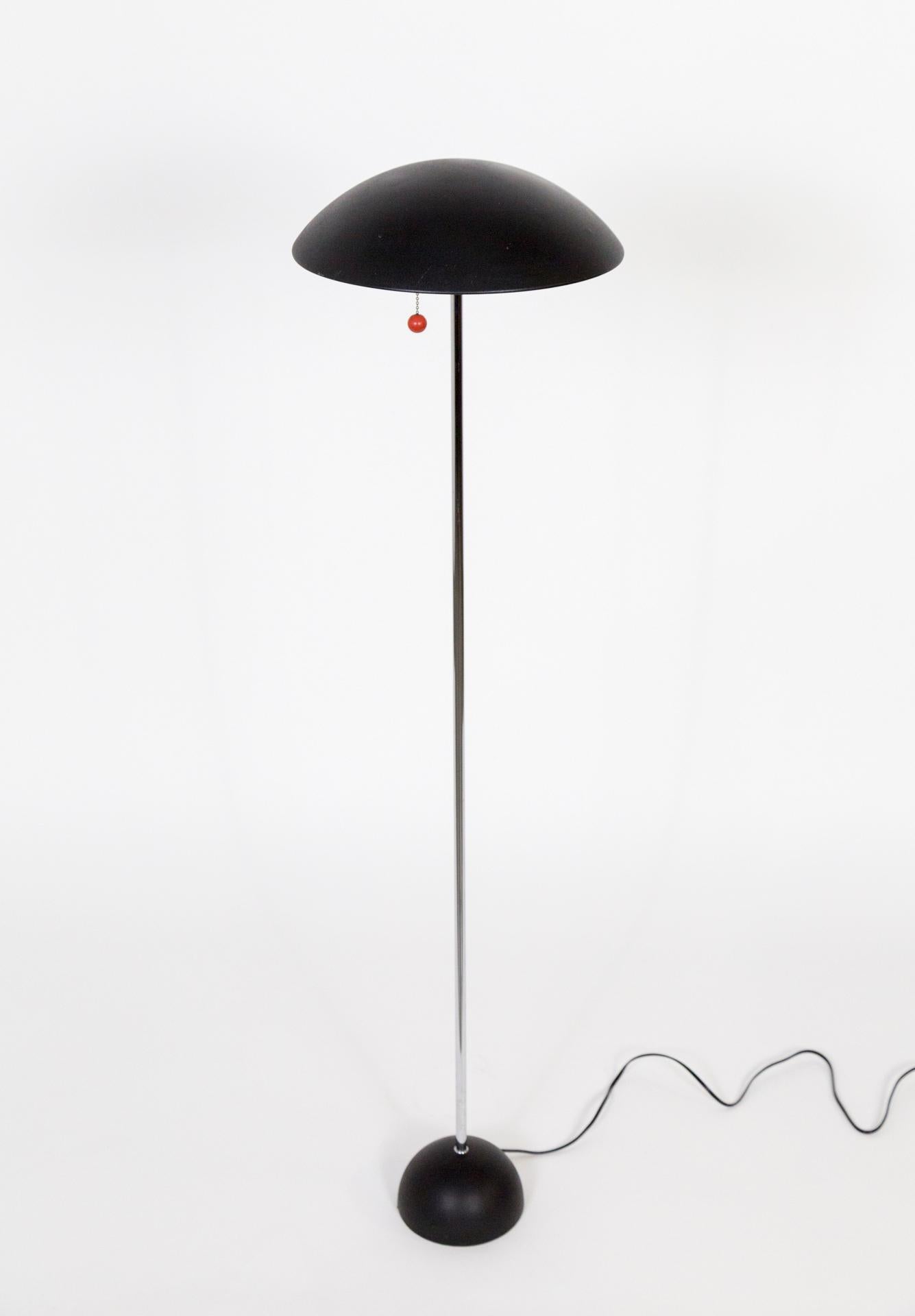 A mid-century floor lamp with a down-light and black, metal, dome shade and pull chain with a red ball detail.  It has a slender, chrome stem and a more pronounced, black dome base.  It is perfect next to a desk or end table.  One medium base