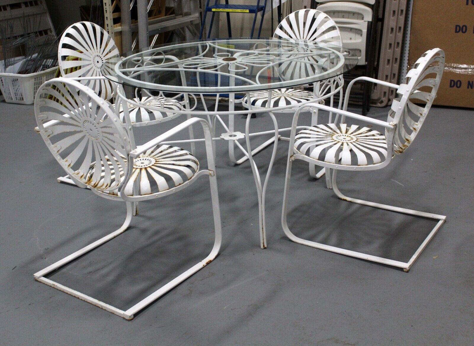 Stunning, French pinwheel iron garden patio set by Francois Carre which includes four spring, cantilevered armchairs and matching round iron base with glass top. In good vintage condition with small signs of rust not impacting the structural