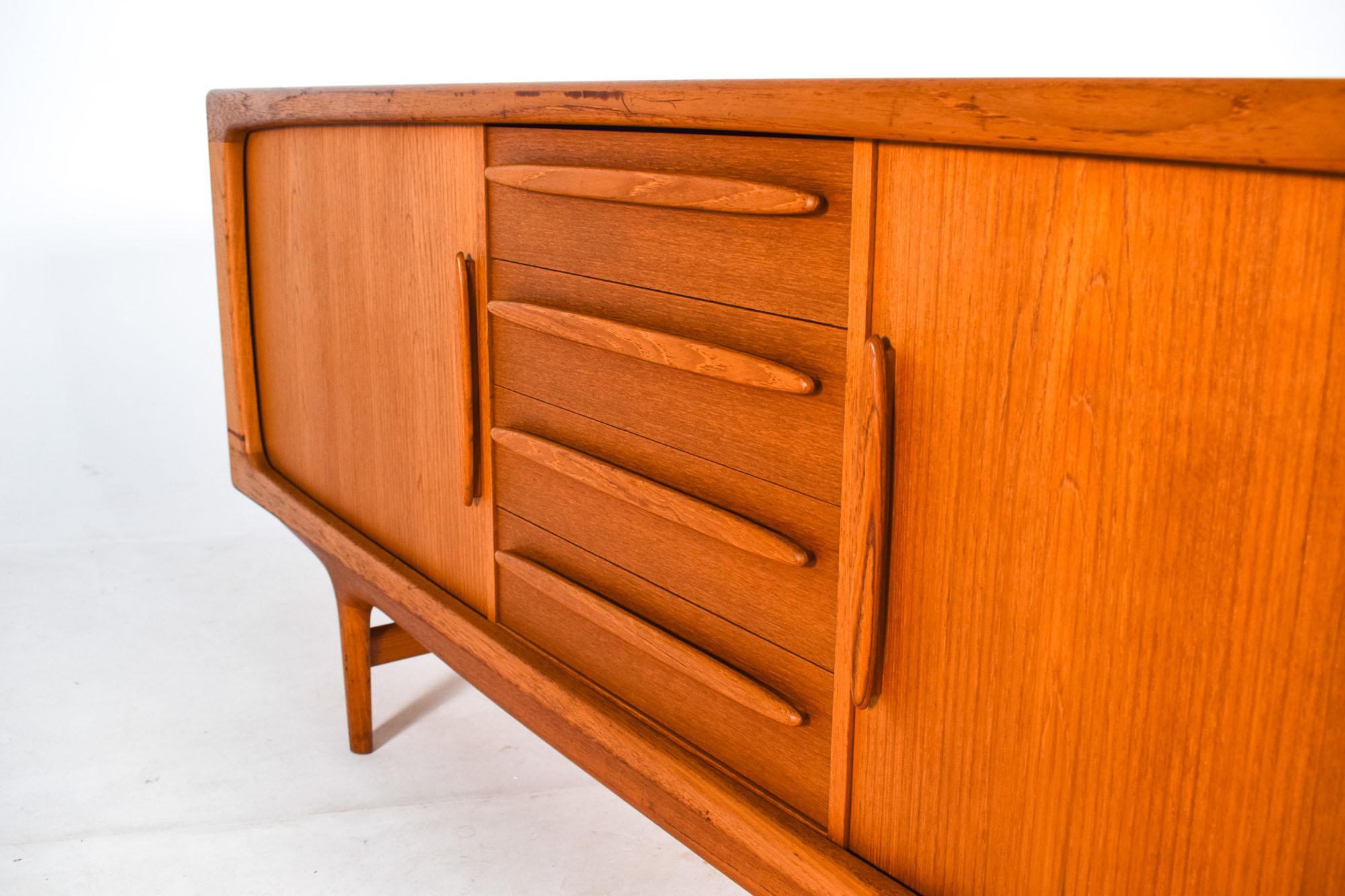This model 230 teak sideboard was designed by Johannes Andersen for Silkeborg. Manufactured in Denmark in the 1960s. Four large center drawers are flanked by a pair of beautiful tambour doors. The sideboard revealing a work of great quality with