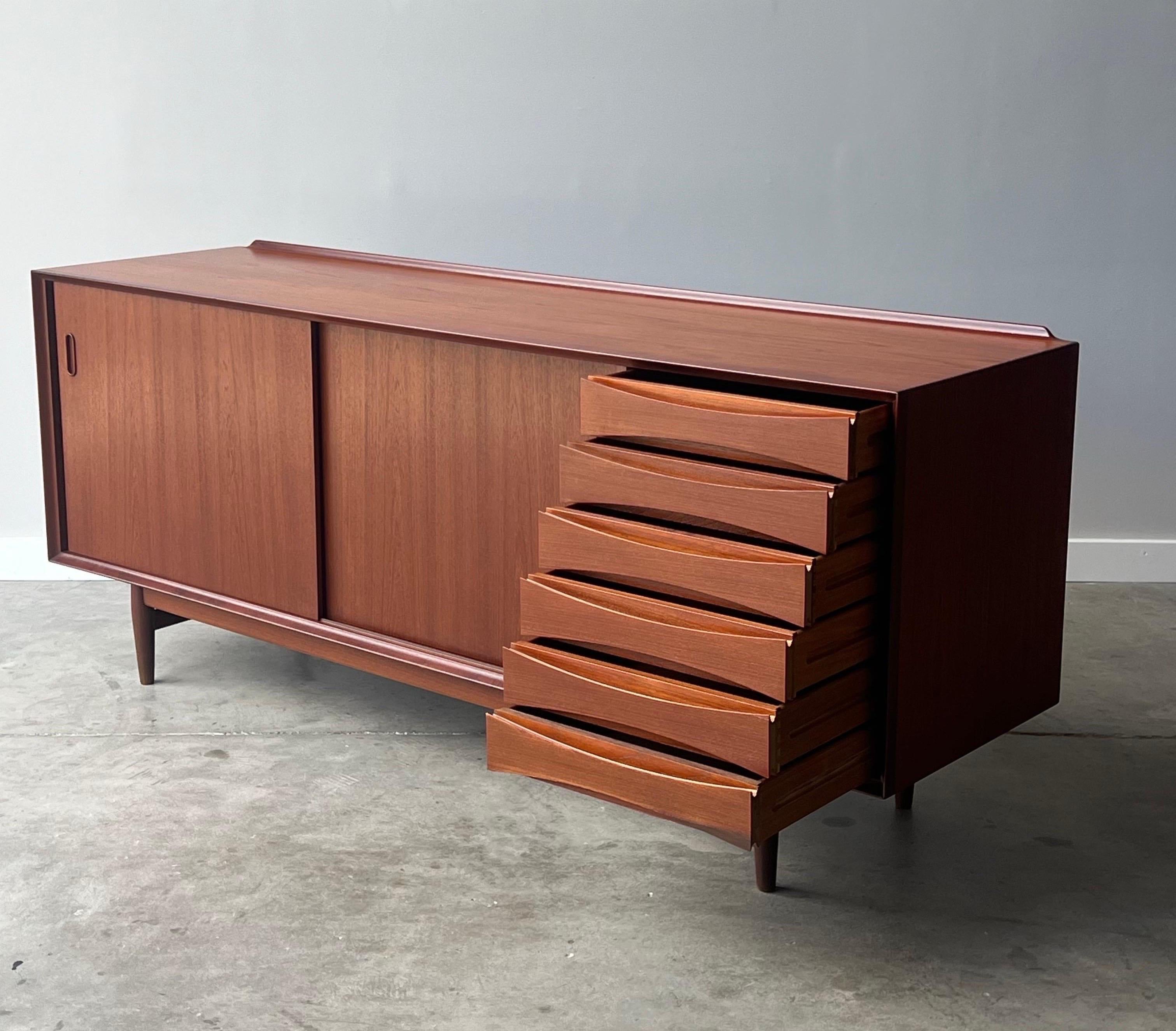 Mid-century iconic credenza or sideboard designed by Arne Vodder for Sibast, circa 1960s. This Model 29 sideboard is extremely well crafted from Danish teak wood.

The left-hand side features two smooth sliding doors with carved inlaid handles that