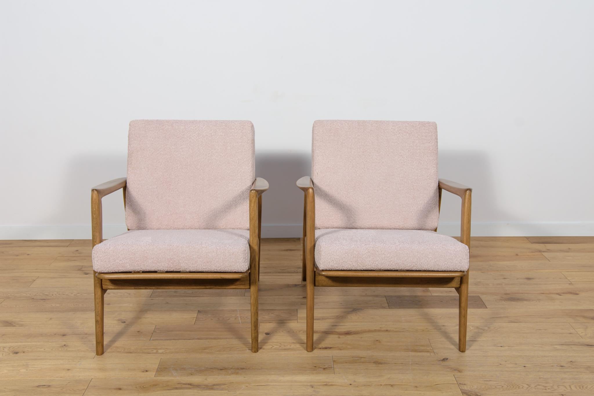 This pair of armchairs was produced by the Polish company Swarzędzka Furniture Factory in 60s. Comfortable armchairs with a unique form. Cushions replaced with new ones, upholstered in high-quality boucle typ fabric in a light pink color. The beech