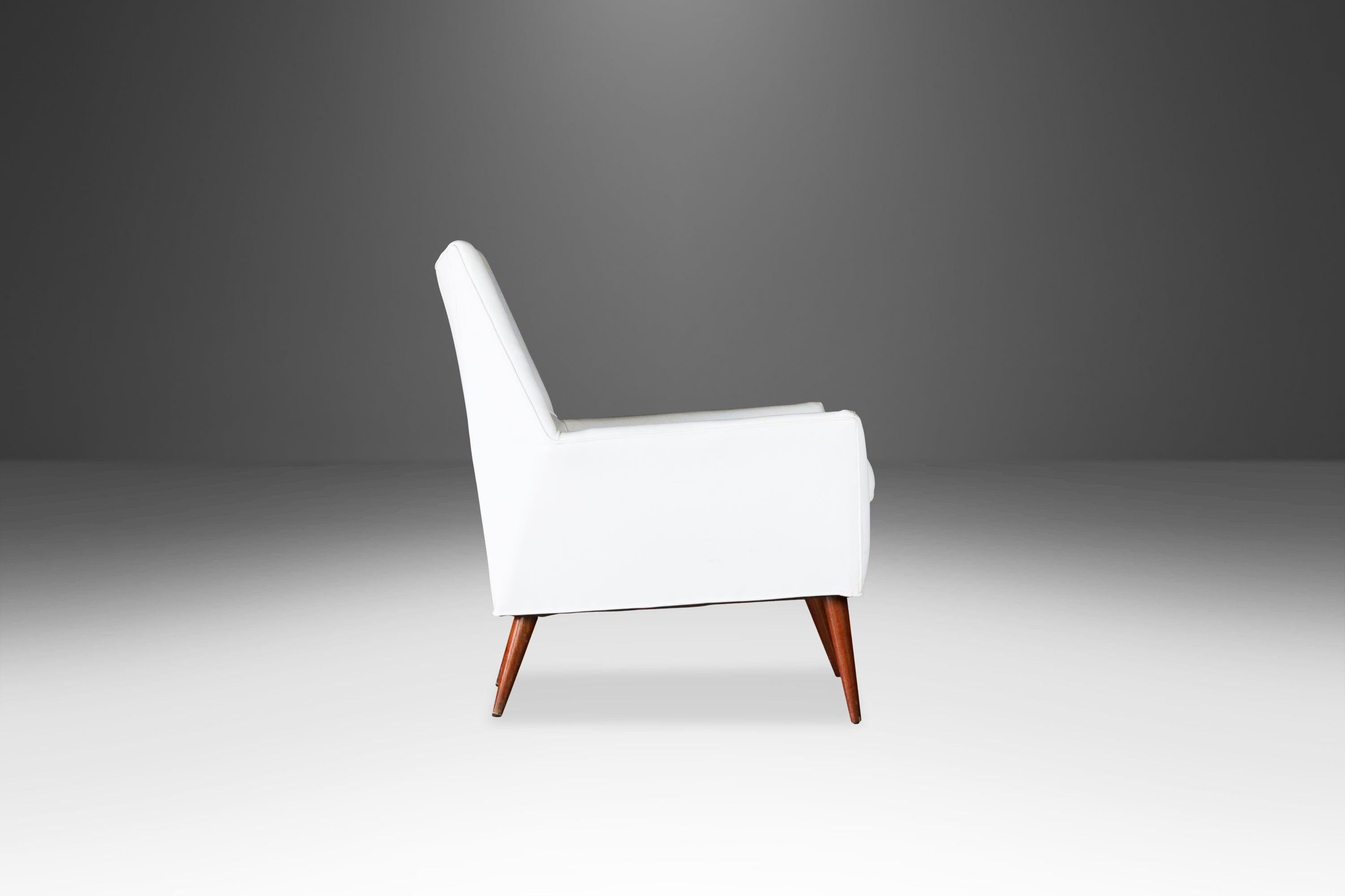 Designed by the visionary Paul McCobb in 1957 the model 3042 “Squirm” lounge chair is an archetypal example of early American Modern design. Featuring the original white leather on a wood and spring frame with turned wood cone-shaped legs this