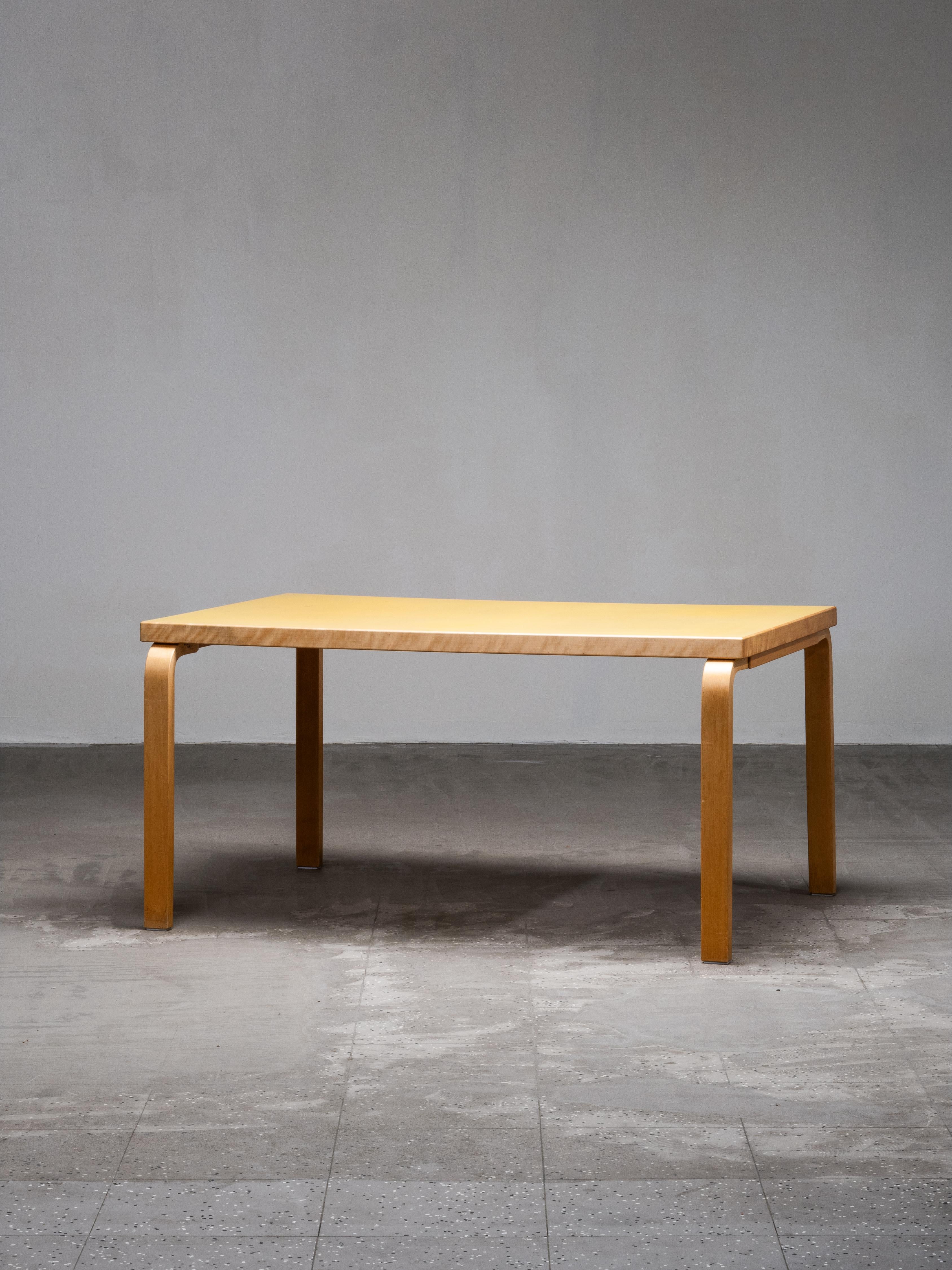 A Mid-Century Model 82 table designed by Alvar Aalto and produced by Artek in Finland, showcasing the designer’s signature bentwood construction and thoughtful use of natural materials. This example features a yellow linoleum top — one of Aalto’s