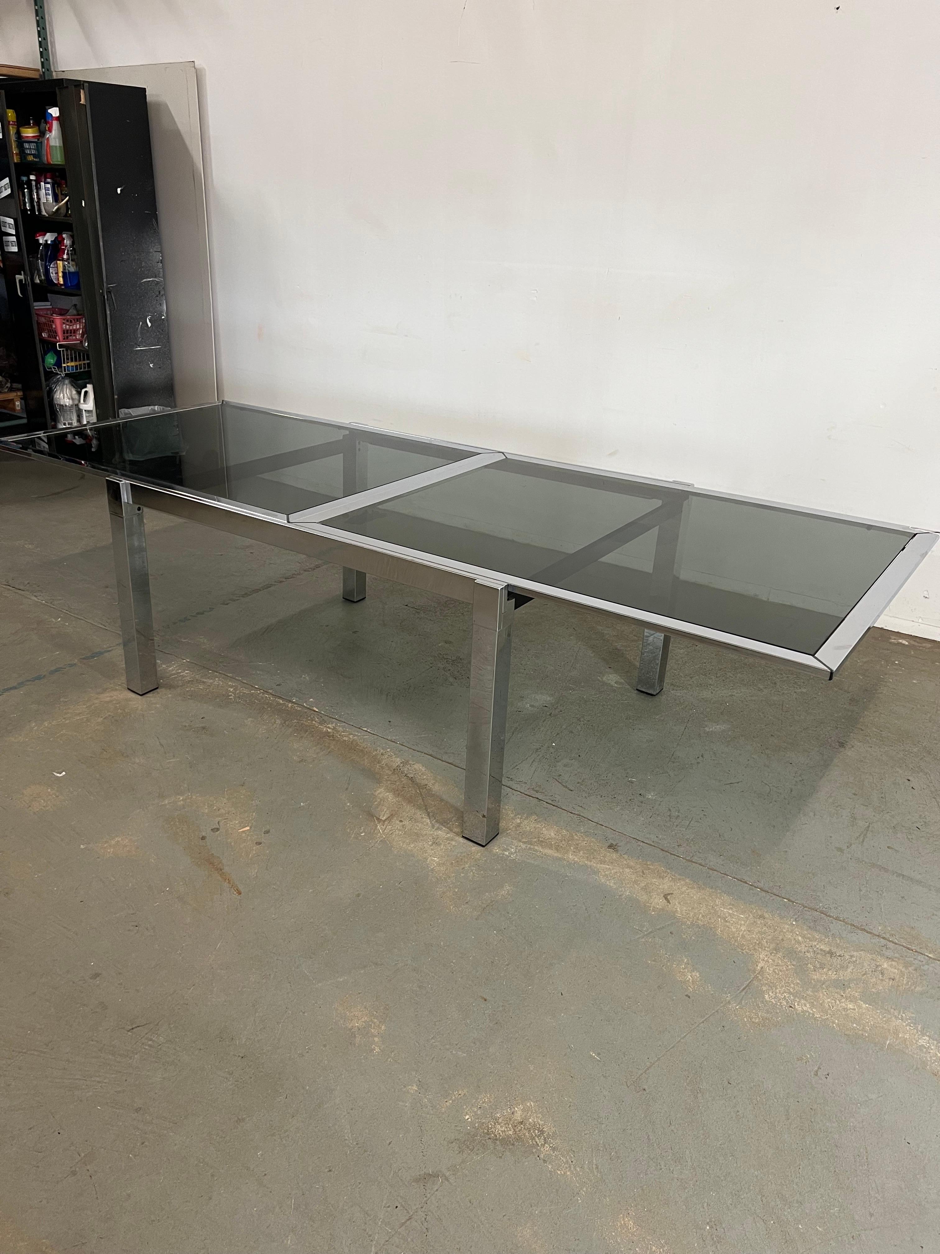 Offered is a midcentury Danish Modern Milo Baughman Chrome Extension Dining Table. The table has a great midcentury look to it. The measurements make this table very versatile, the table can be displayed at 55” and can open when entertaining to