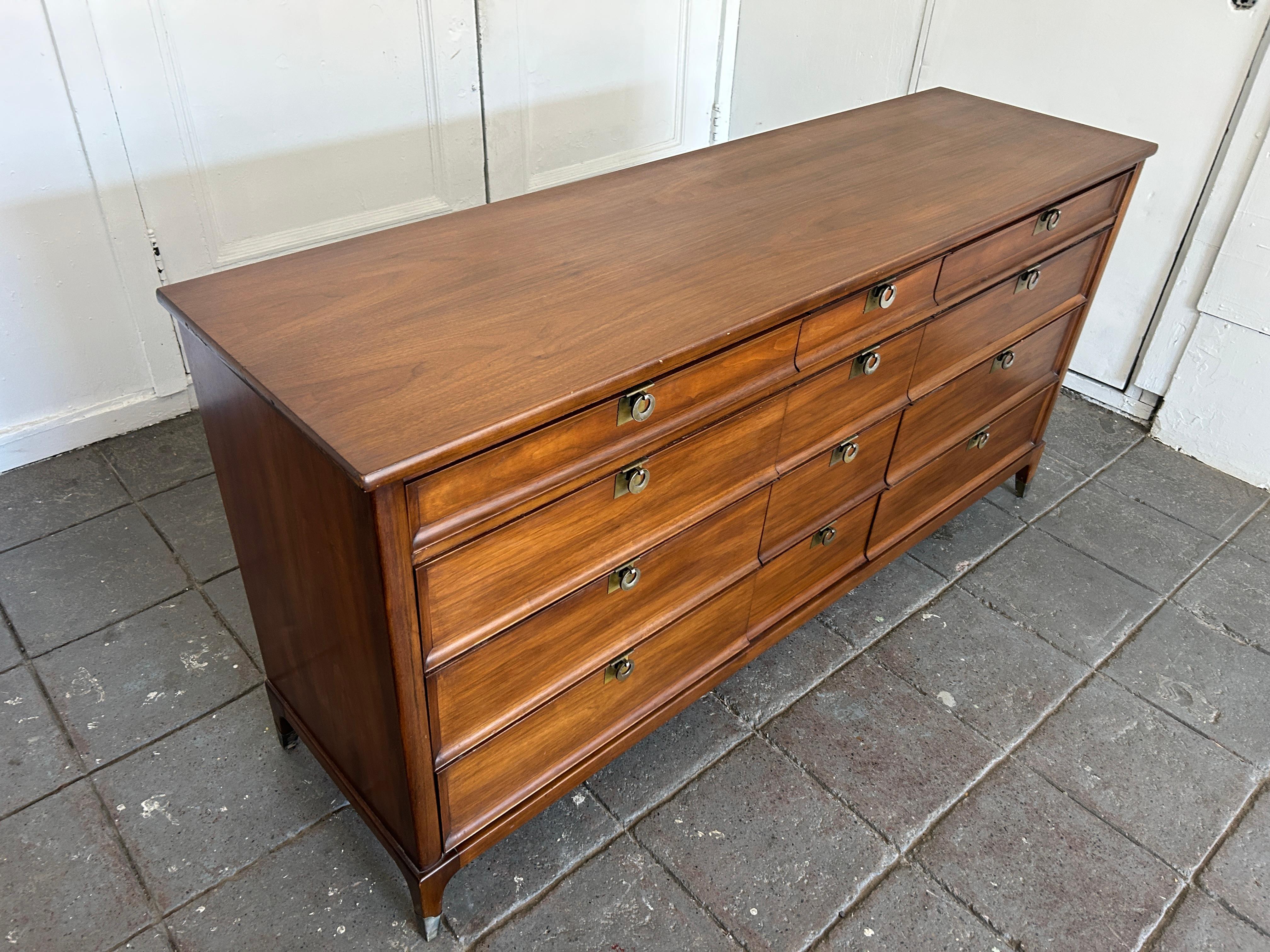 Fabulous Mid-Century Modern 12 drawer Walnut dresser credenza ring brass pull handles. Very nice dresser with 12 drawers - lots of drawer space. Each drawer has a hanging brass ring pull. The dresser is finished in a medium walnut color that sits on