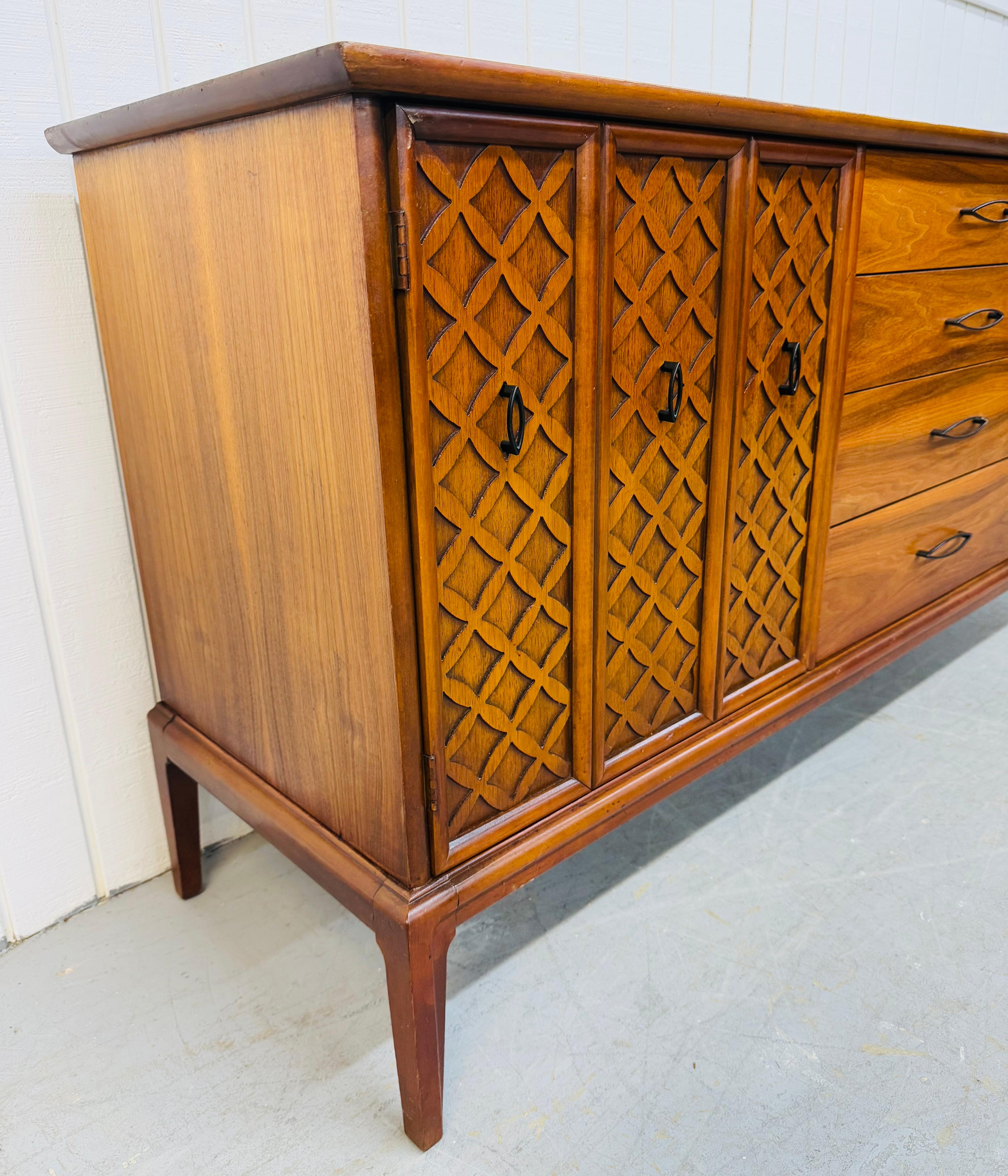 Questo annuncio si riferisce a un comò in noce a 12 cassetti in stile Mid-Century Modern. Caratterizzato da un design lineare, un'anta a reticolo che si apre su quattro cassetti nascosti, otto cassetti più grandi sul lato destro, ferramenta