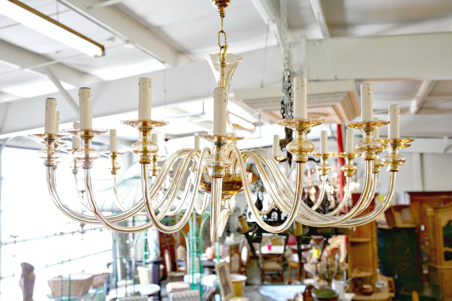 Stunning, handblown chandelier in the modern neoclassical tradition featuring eighteen scroll form arms, each ending in a bobeche, that connect to an inverted domed form and central etched body, all in champagne glass. There are brass fittings