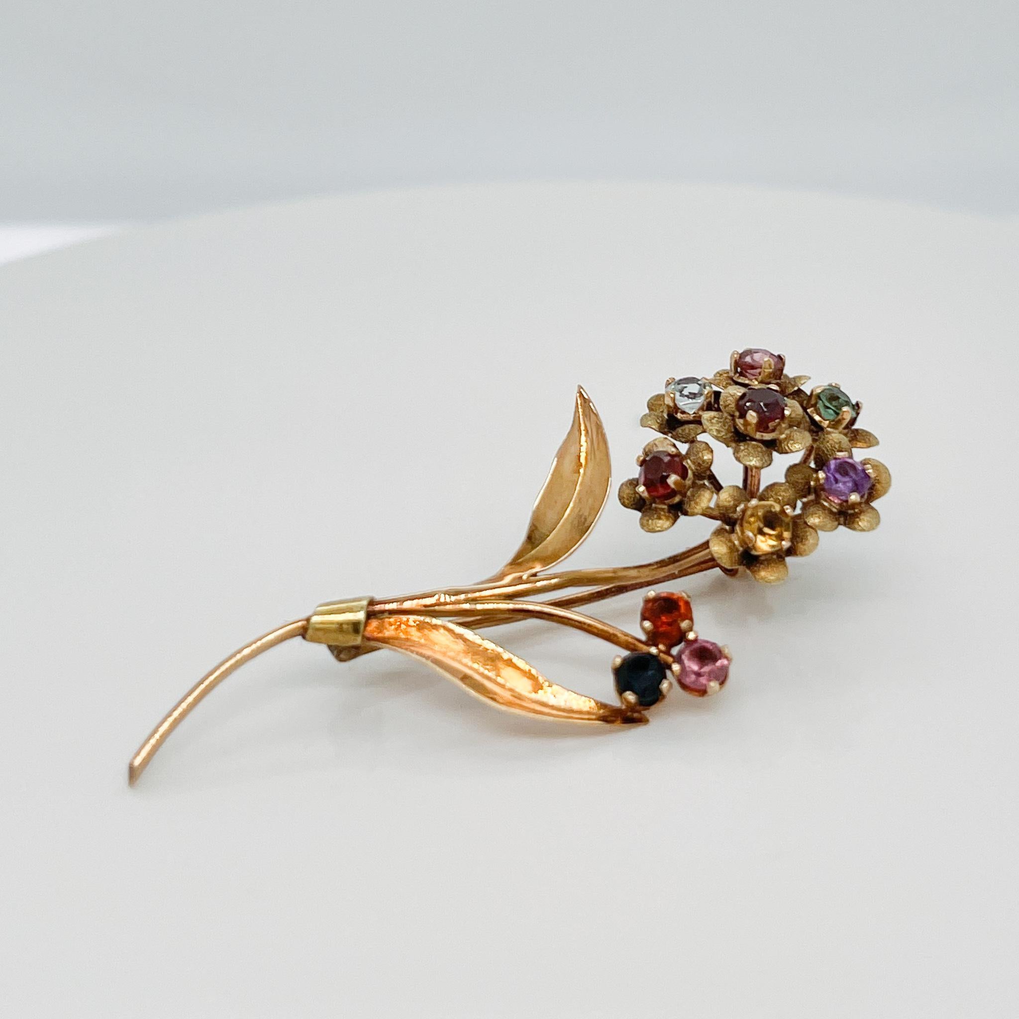 A fine Mid-Century flower brooch or lapel pin.

In 18k gold.

With multiple prong-set faceted gemstones set as flower heads in a small bouquet.

Gemstones include pink & green tourmalines, amethyst, citrines, and garnets. 

Simply a wonderful