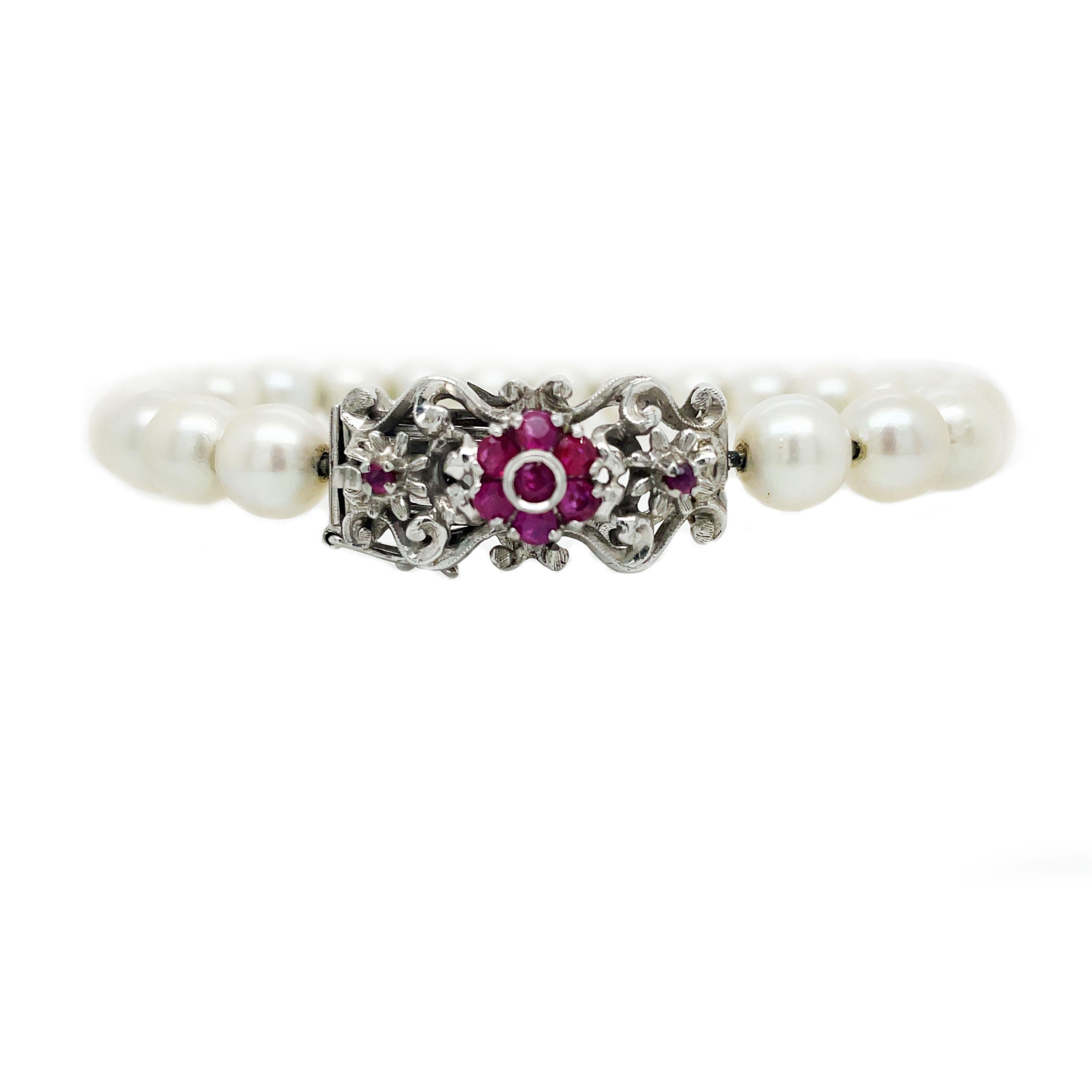 This is a fabulous Mid-Century Modern bracelet crafted in 18K white gold showcasing beautiful white pearls and vibrant rubies adorning the clasp. A flowing floral cluster of dazzling rubies framed in bright 18K white gold forms the unique decorative