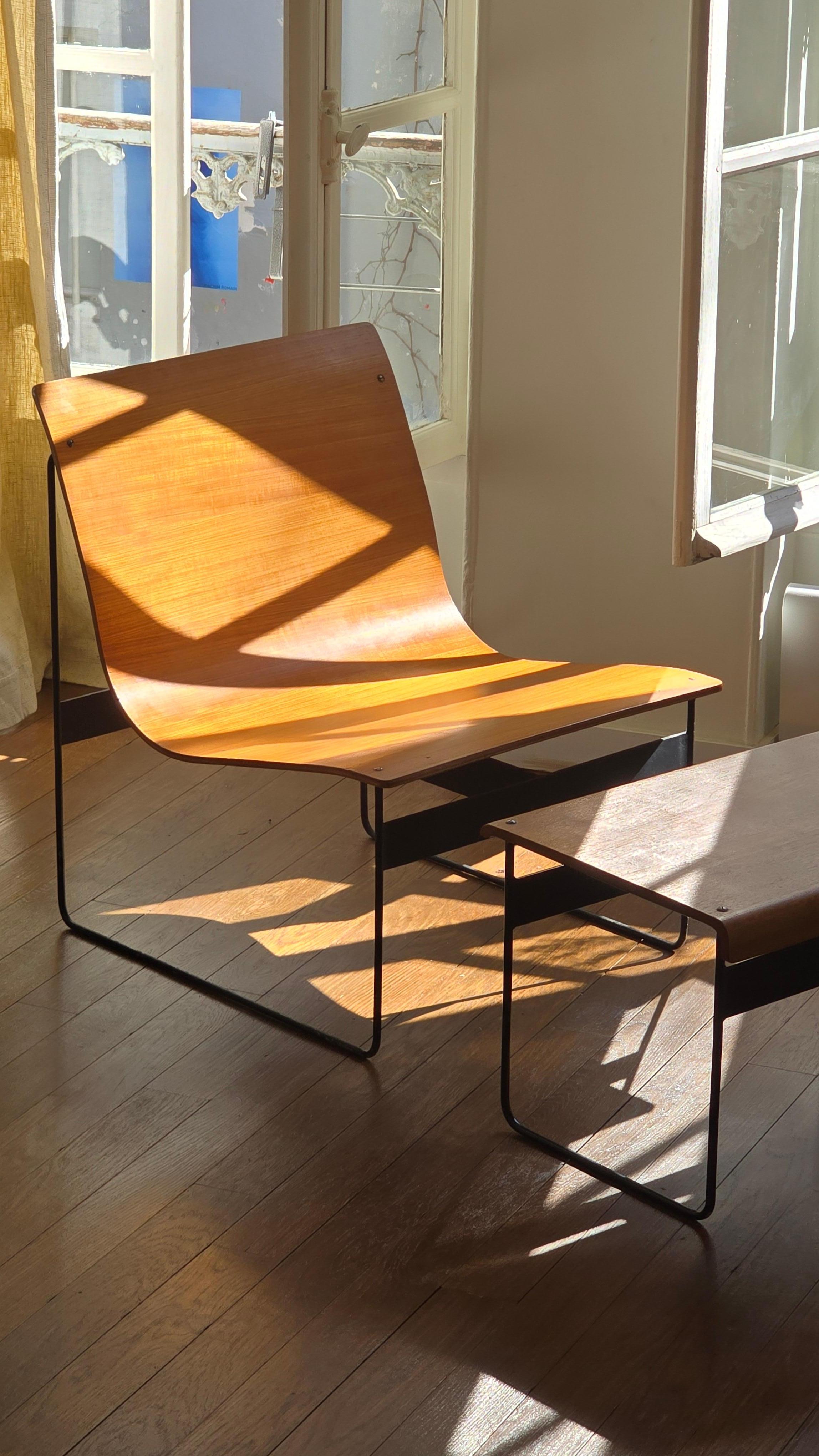 Elegant 1950s lounge chair by Gunter Renkel, accompanied by its original matching ottoman. The design combines a minimalist steel frame with a curved plywood seat and footrest, creating a refined and architectural silhouette. The clean lines and