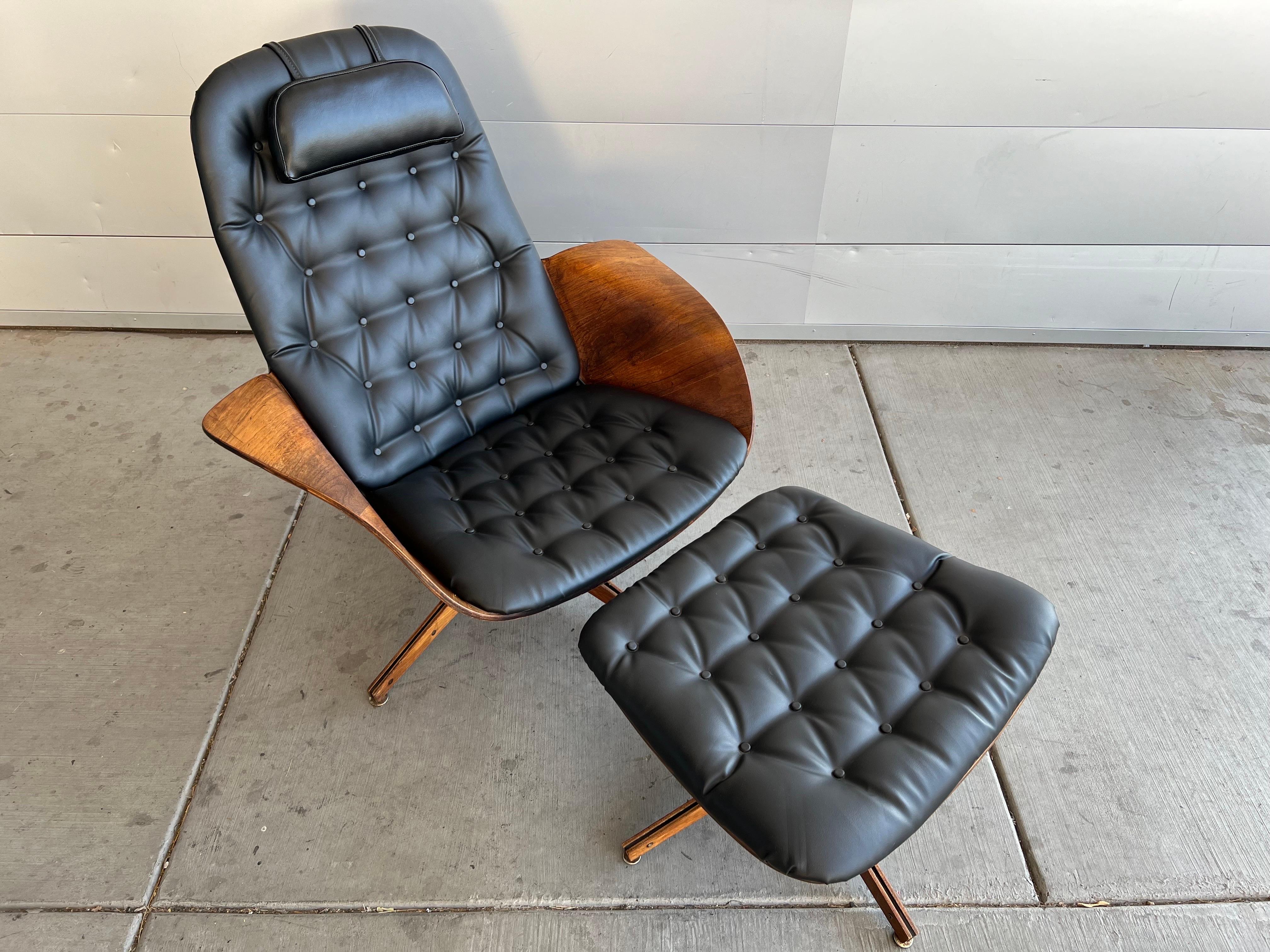 1960s vintage Mr. Chair and ottoman by George Mulhauser for Plycraft. This iconic mid century modern chair features sculptural bent walnut armrests and brand new black vinyl tufted upholstery. The chair and ottoman both swivel. The chair has a