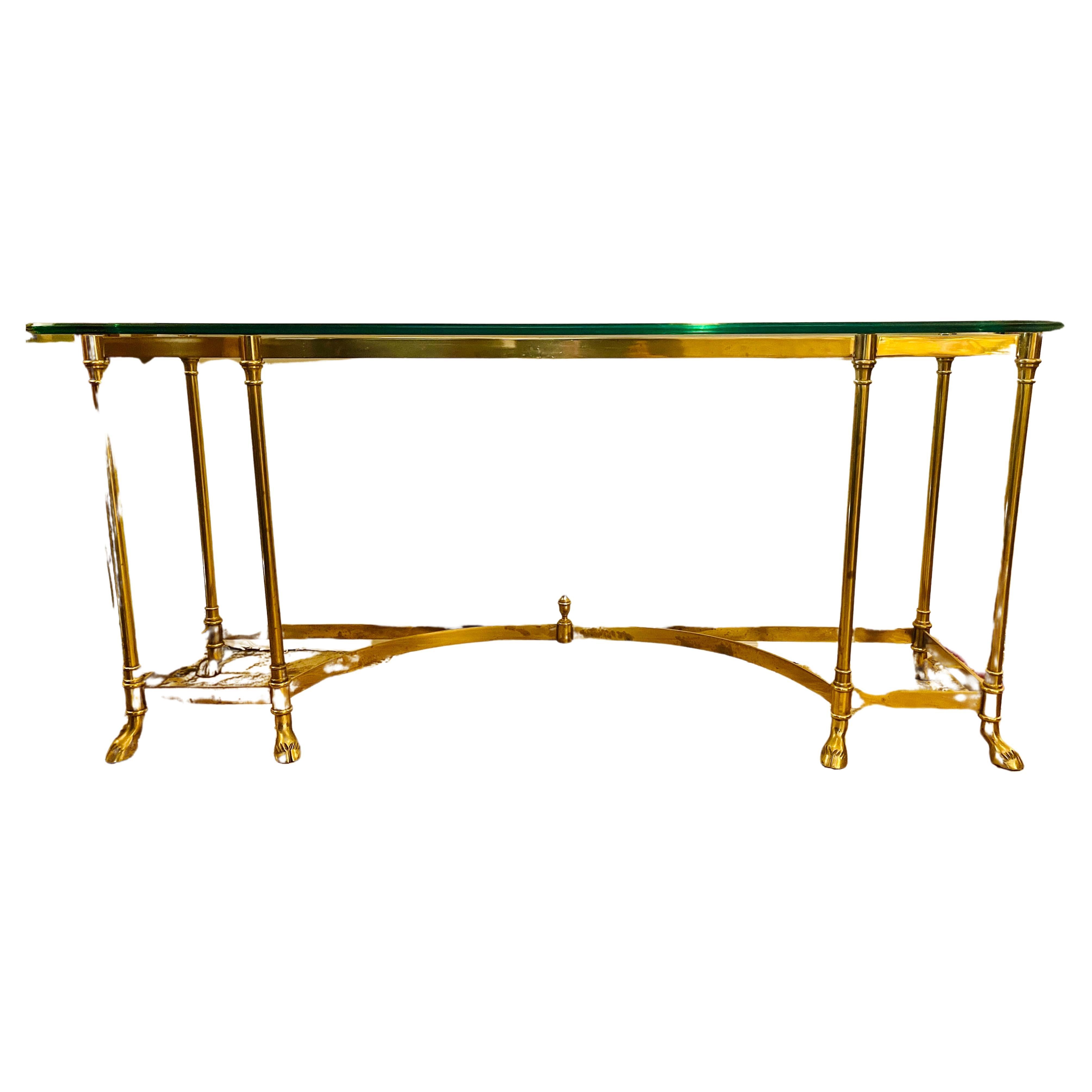 Vintage Mid Century solid brass Maison Jansen glass top console table.
This is from the 1970's and note the brass is solid and features the highly coveted hoof feet. The piece is iconic and would benefit from a quick brass polish as it has some spot