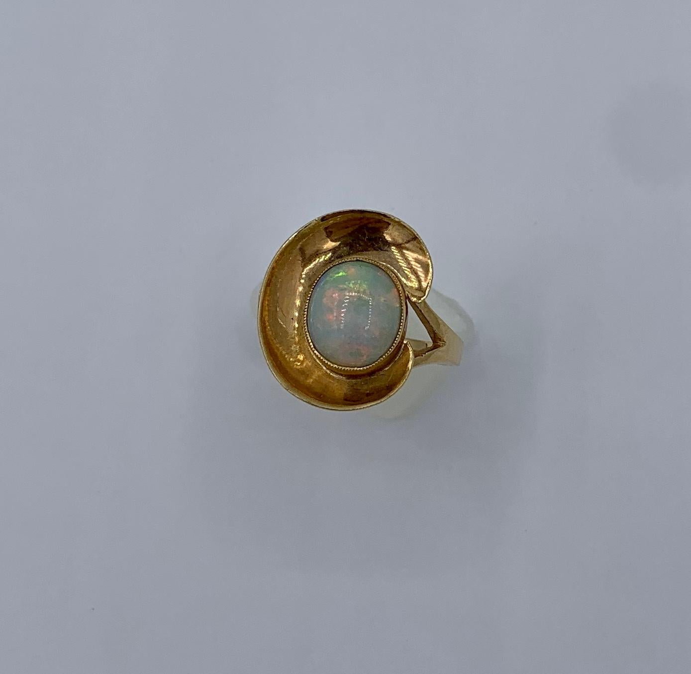 THIS IS A WONDERFUL MID-CENTURY MODERNIST EAMES ERA 2 CARAT OPAL RING IN 14K YELLOW GOLD WITH A STUNNING OVAL OPAL CABOCHON GEM.
The effect of the gorgeous natural opal in the wondrous mid-century geometric design in 14K yellow gold create a magical