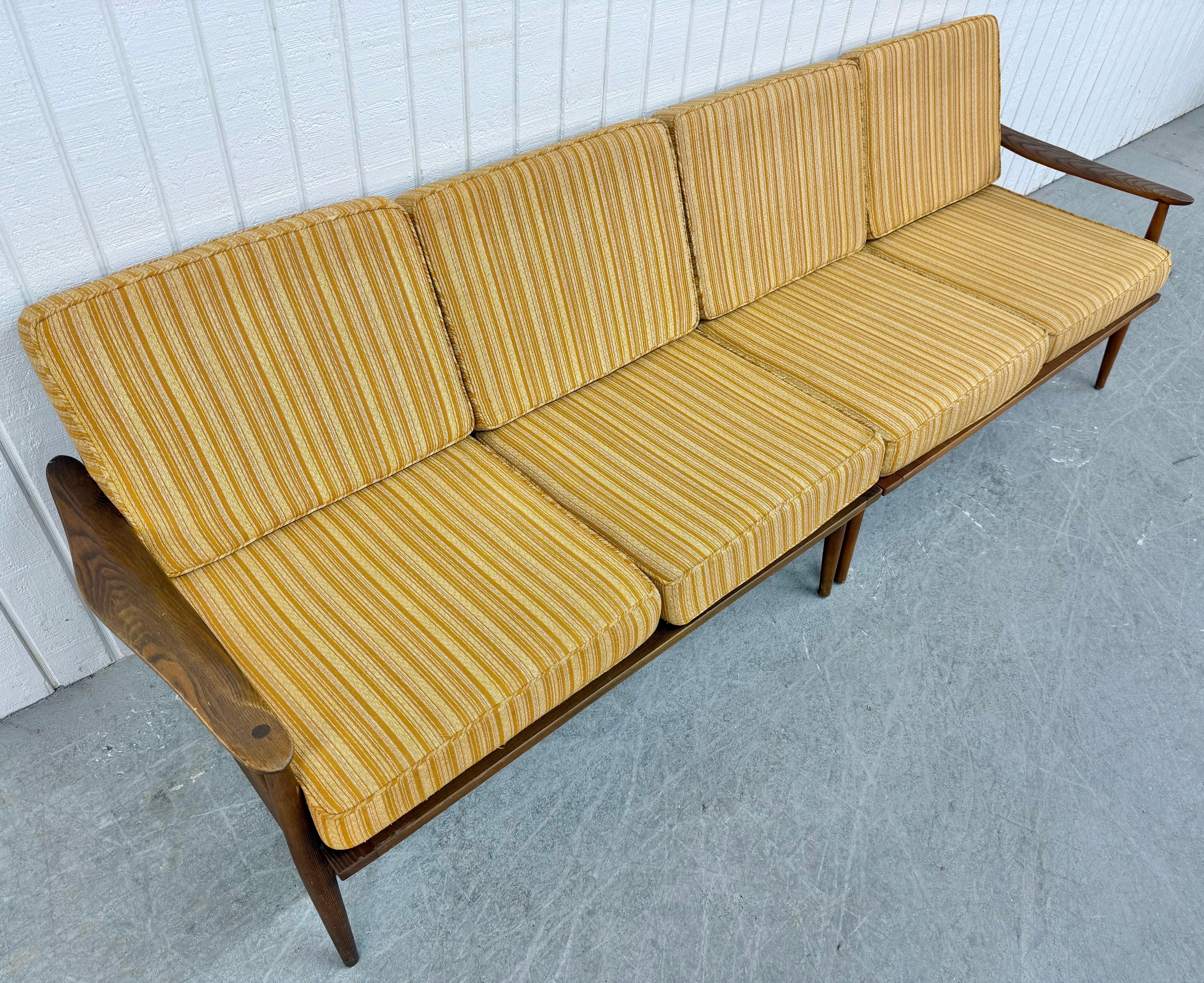 Questo annuncio si riferisce a un divano in legno di noce di epoca moderna. Design lineare in due pezzi, struttura in noce, braccioli in legno su ogni estremità, schienale a fuso, cuscini originali imbottiti dorati e rimovibili, cinghie di sostegno