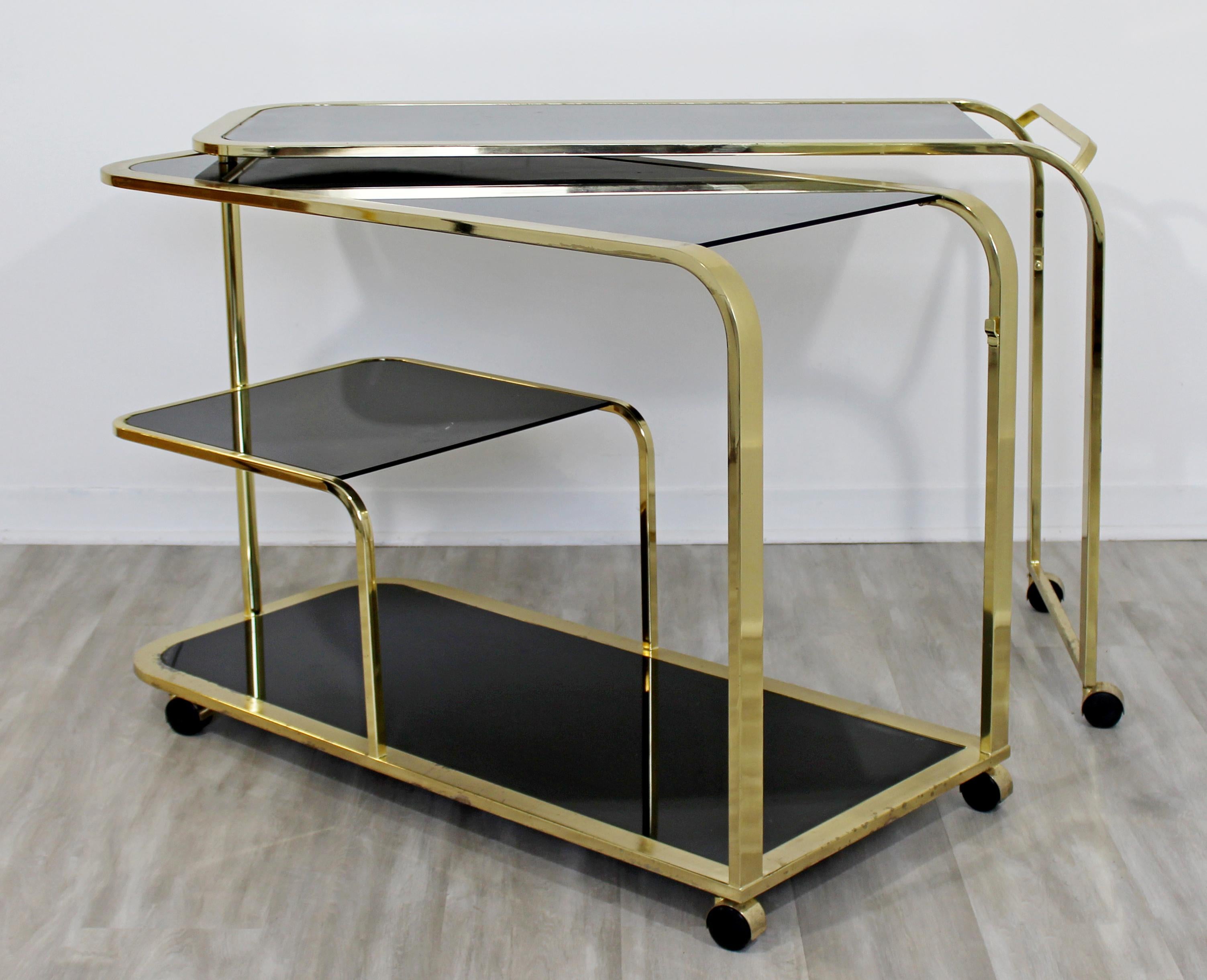 For your consideration is a wonderful, expandable, rolling bar or service cart, with four black glass tops, by The Design Institute of America, circa 1960s. In good vintage condition, with a heavy patina. The dimensions closed are 45