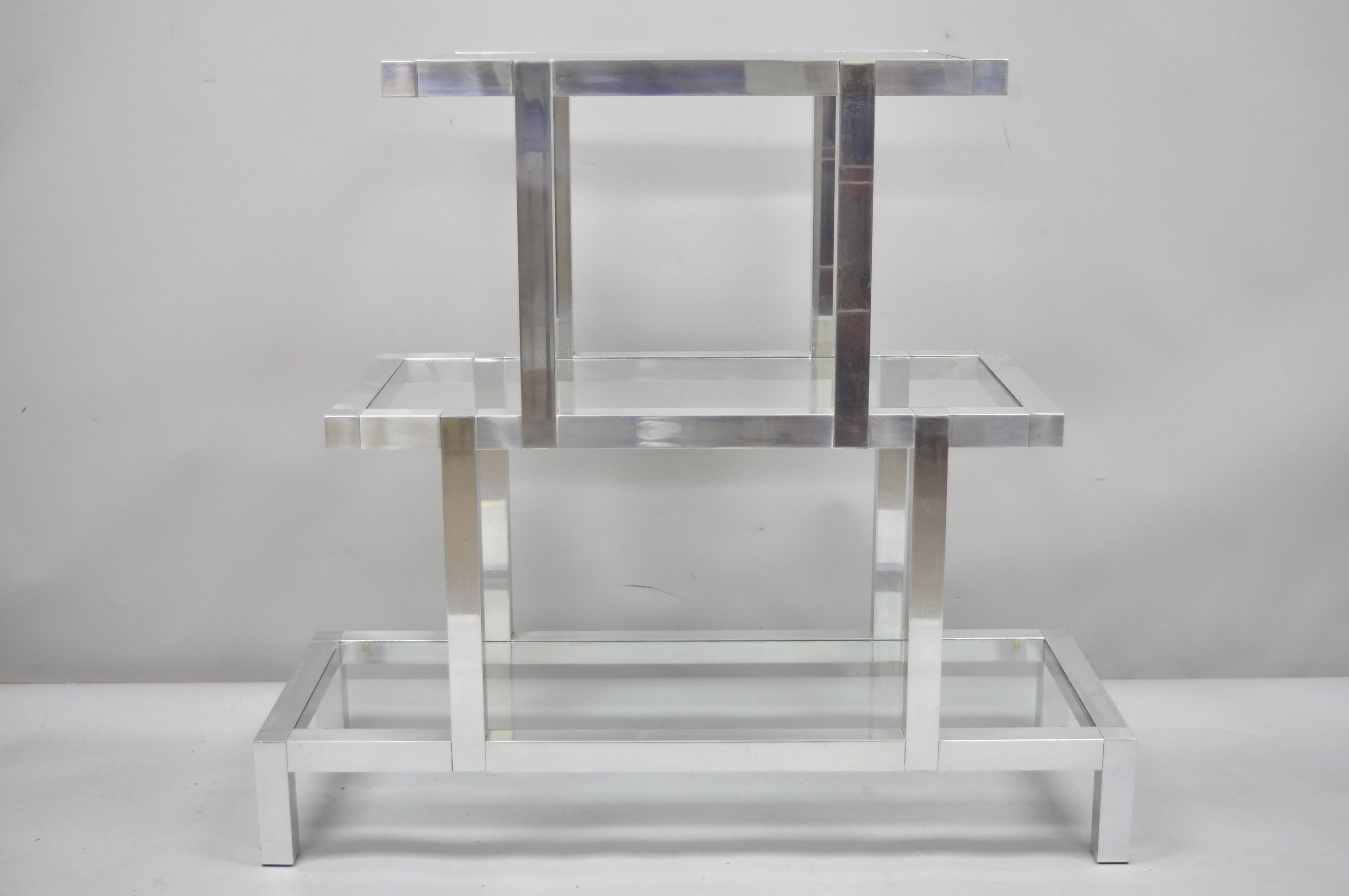 Mid-Century Modern three-tier aluminum & glass Milo Baughman style display shelf. Item features a three-tier cast aluminum frame, glass shelves, very nice vintage item, clean modernist lines, circa mid-20th century. Measurements: 36.5