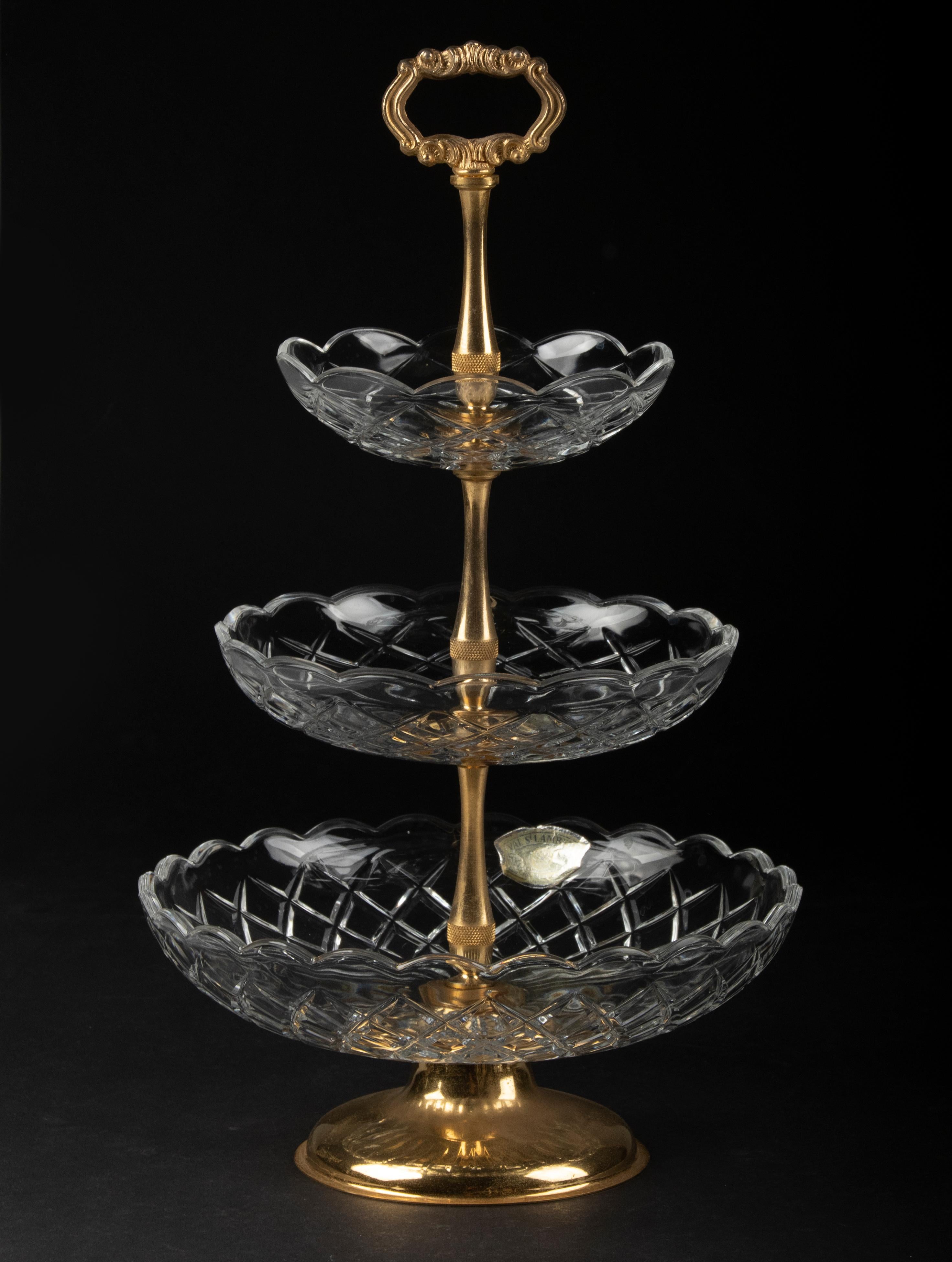 Schöner 3-Schicht-Kristallständer von dem belgischen Designer Val Saint Lambert. Der Rahmen ist aus vergoldetem Metall gefertigt. Die Kristallschalen haben einen schönen Schliff mit Bögen und gewellten Rändern. Der Stand stammt aus der Zeit um 1960.