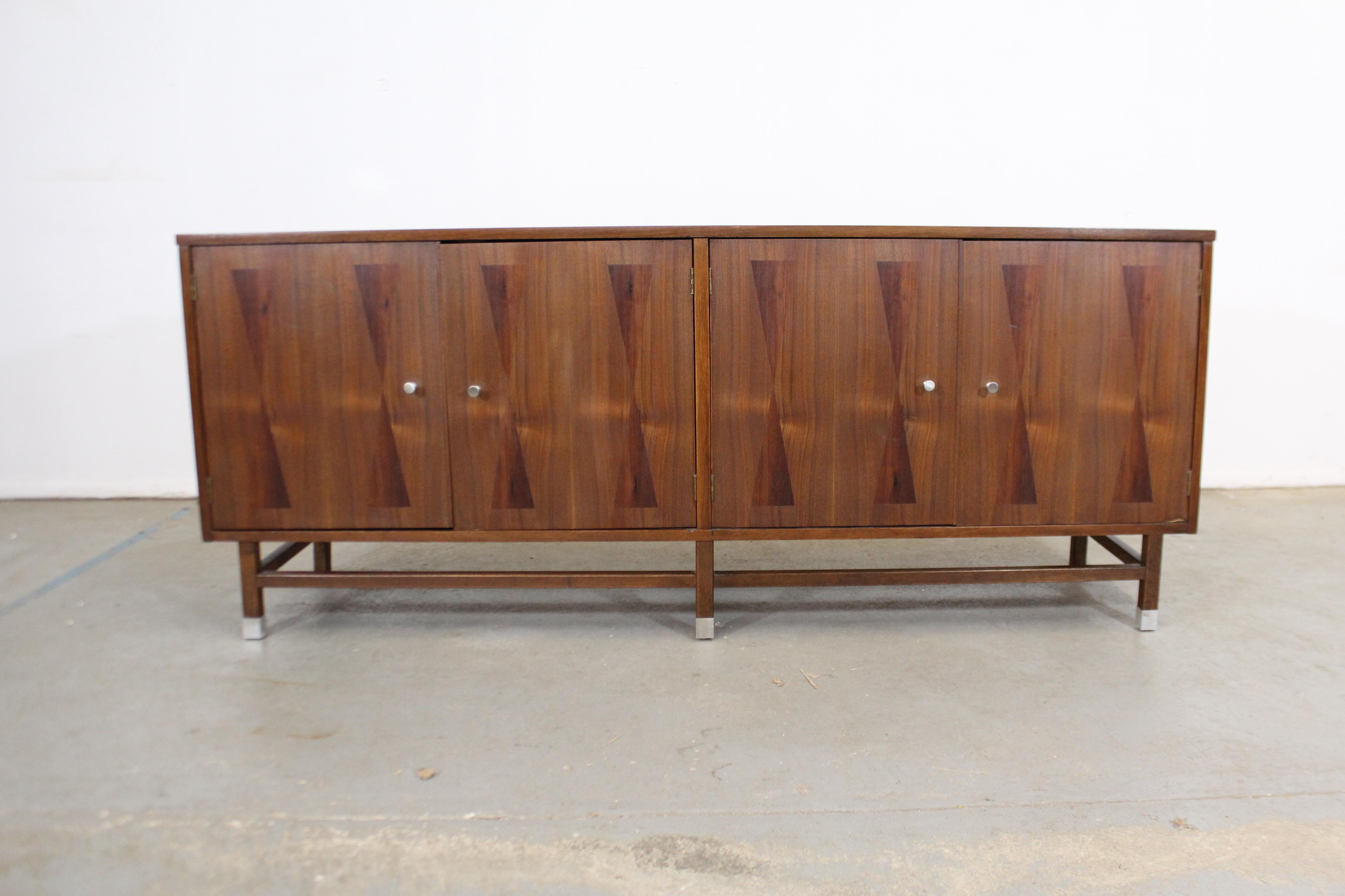 Offered is a vintage Mid-Century Modern walnut credenza with four parqueted doors. Includes inner shelving and three dovetailed drawers. One drawer has dividers with felt lining for silverware. It has been refinished and its pulls have been replaced