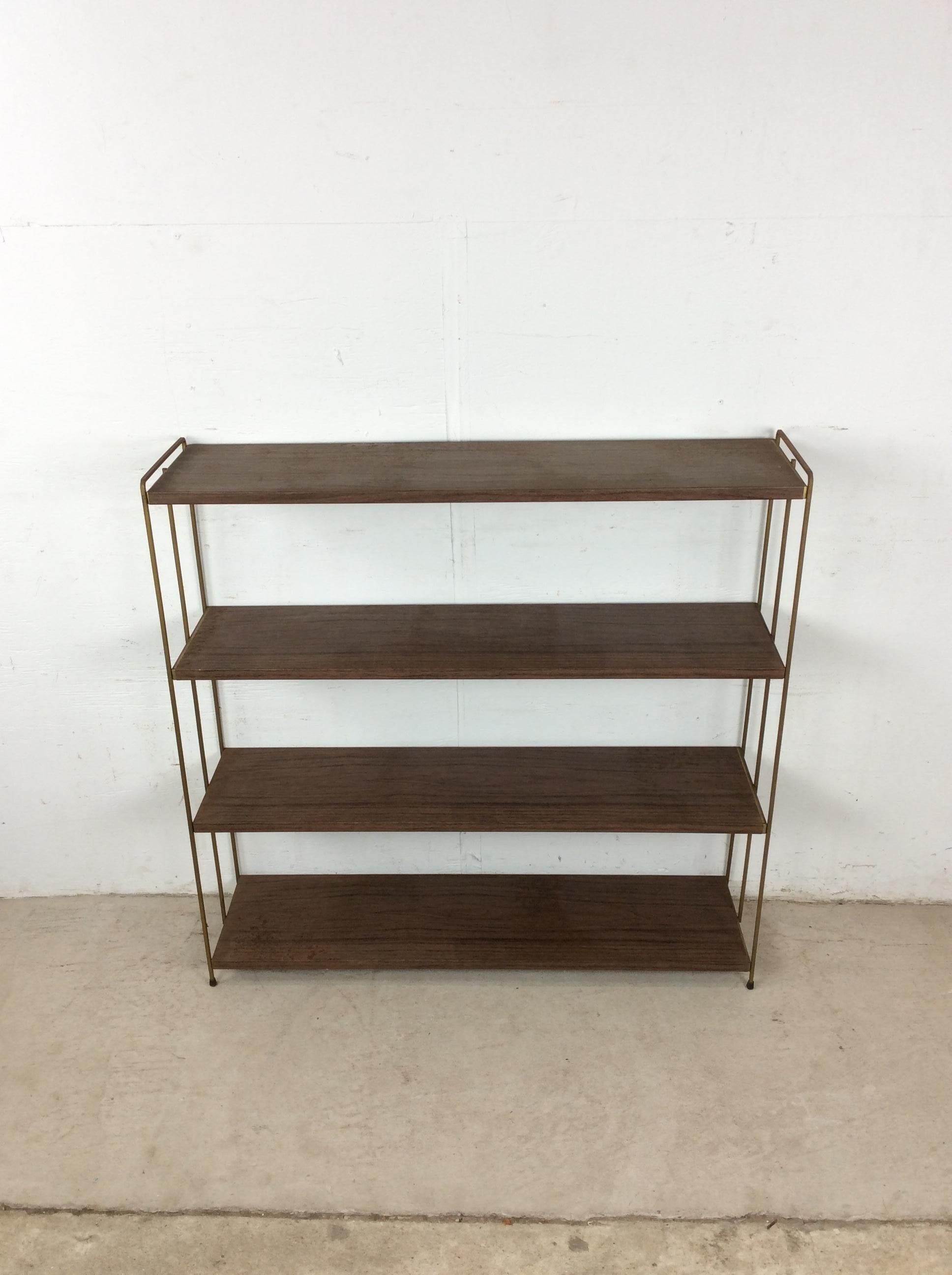 Questa libreria classica della metà del secolo scorso è caratterizzata da quattro ripiani in metallo con vernice marrone originale e stampa in finto noce, gambe e piedi in ottone. u2028u2028Ho a disposizione altre due mensole identiche e una mensola