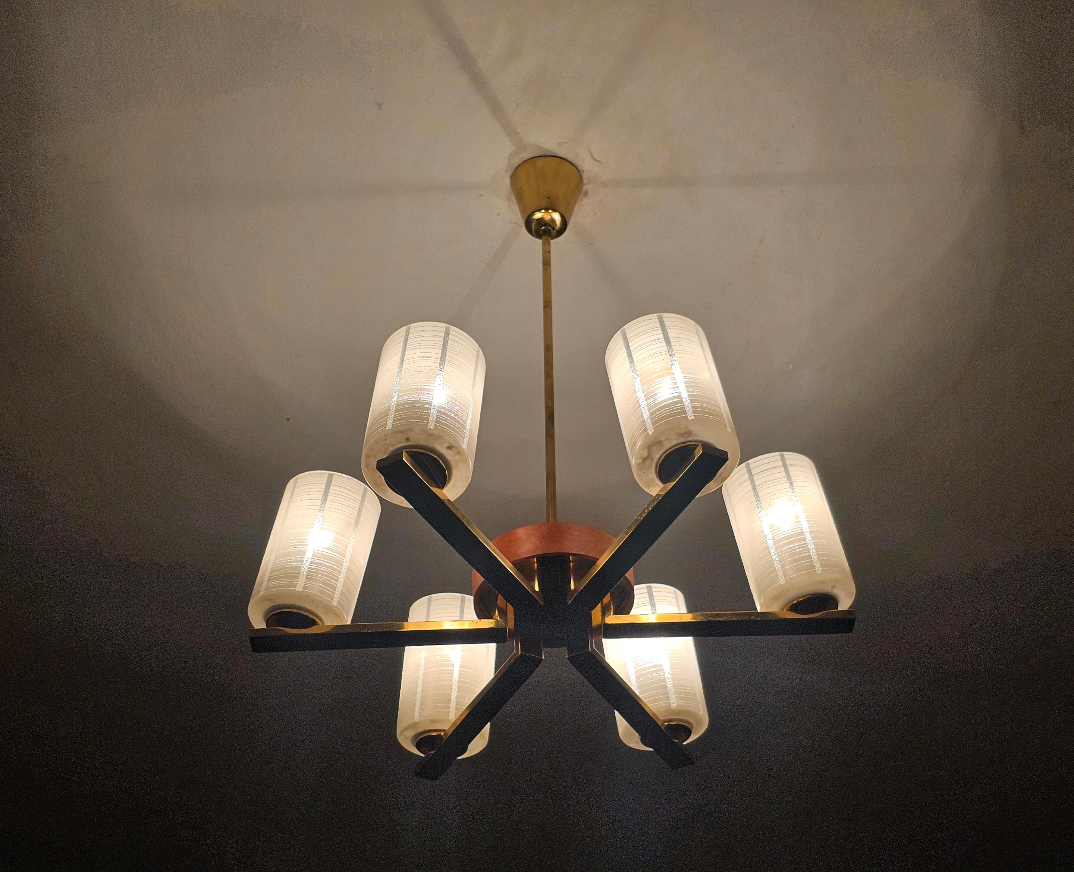 Vous trouverez dans cette annonce un élégant lustre à 6 bras de lumière en laiton et teck, avec des abat-jours en verre dépoli.  Simple et élégante, comme doit l'être une pièce typique du Mjd Century Modern. Fabriqué en Autriche dans les années