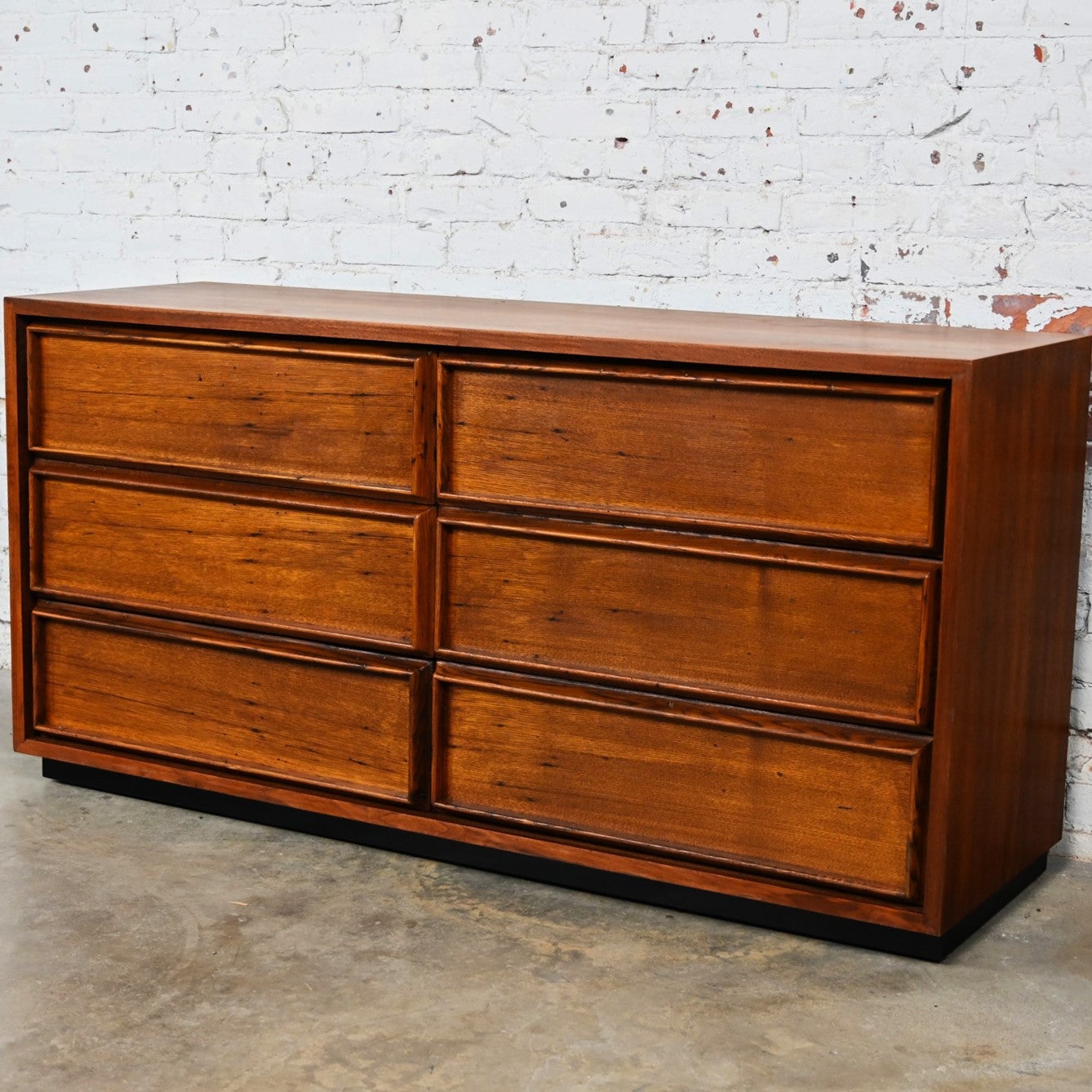 Fabulous vintage Mid Century Modern 6 drawer dresser by Dillingham Manufacturing Company. Comprised of a walnut case rustic pecky cypress drawers, and a recessed black painted plinth/floating base. Beautiful condition, keeping in mind that this is