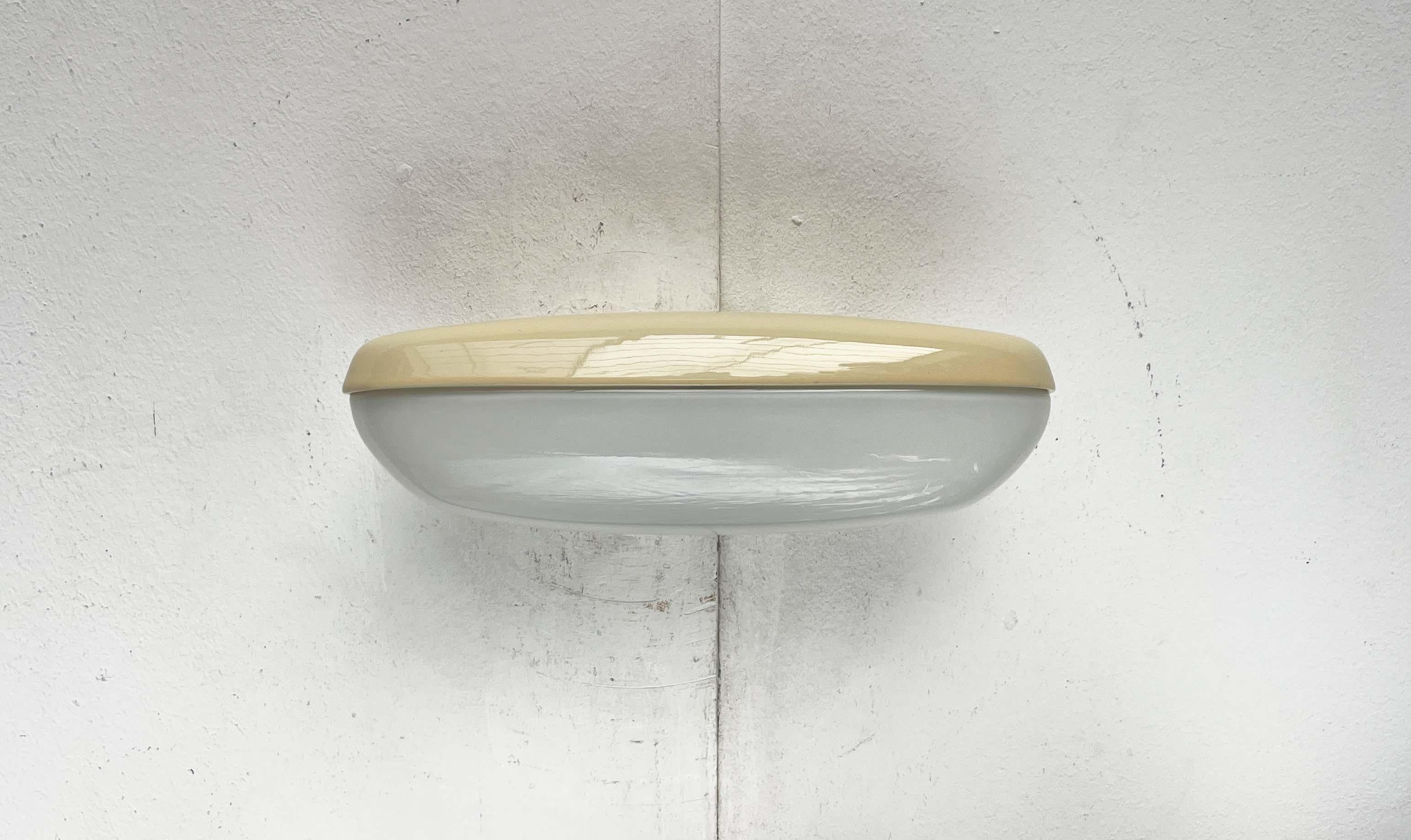 Lámpara de espejo clásica de mediados de siglo de Lindner, basada en un diseño de Wilhelm Wagenfeld de los años 50. Se muestra aquí en el raro color amarillo.

Un diseño funcional, elegante y, por tanto, atemporal. La base de porcelana de forma