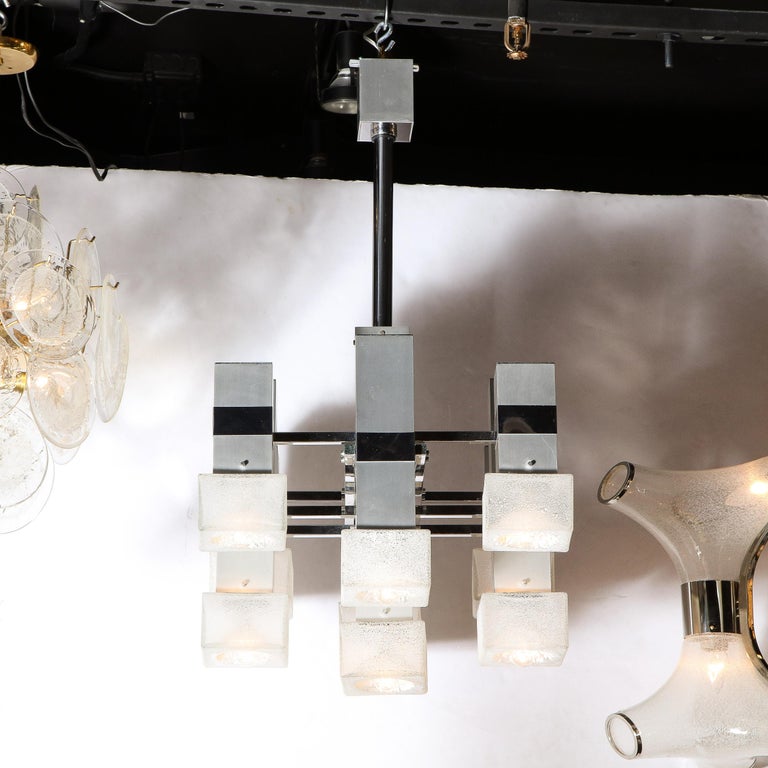 This stunning Mid Century Modern chandelier was realized by the fabled 20th century designer, Gaetano Sciolari in Italy circa 1970. It offers a grouping of eight volumetric rectangular cubic bodies in brushed chrome attached via lustrous chrome