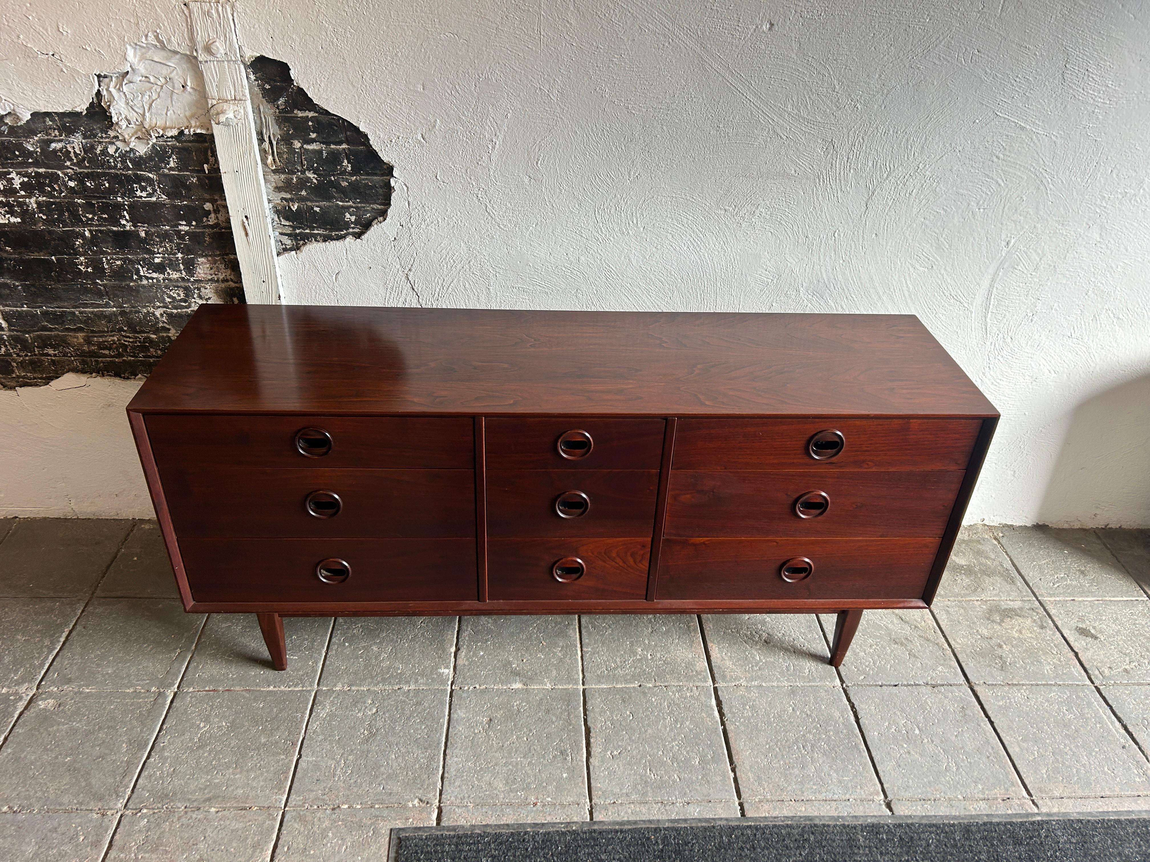 Unique mid century modern walnut 9 drawer dresser with carved handles. Dark reddish walnut wood Danish rosewood style with circular eye carved handle / Pulls. Dovetail solid oak drawer construction. Beautiful wood grain. Made in USA circa 1960.